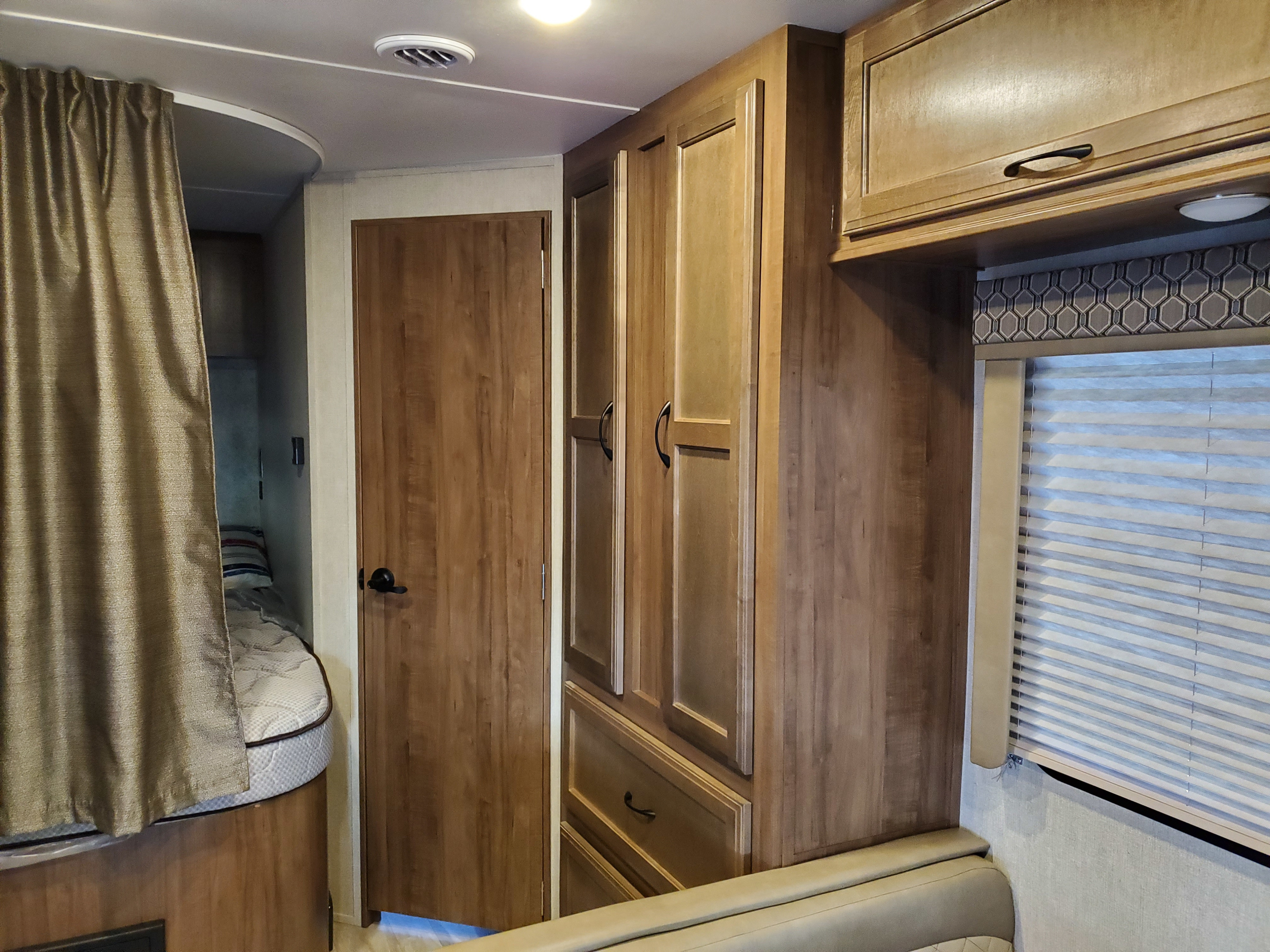 Spacious RV rental interior with wooden cabinetry, a bunk bed area with privacy curtain, and comfortable seating.. Gulf Stream Conquest 2019
