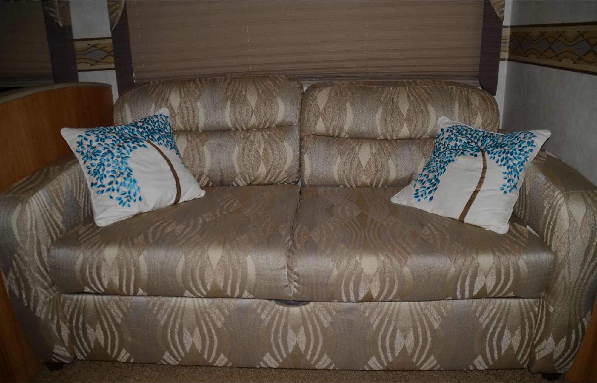 This RV rental features a comfortable sofa with unique tree-design pillows, enhancing your mobile living space.. Coachmen Mirada 2011