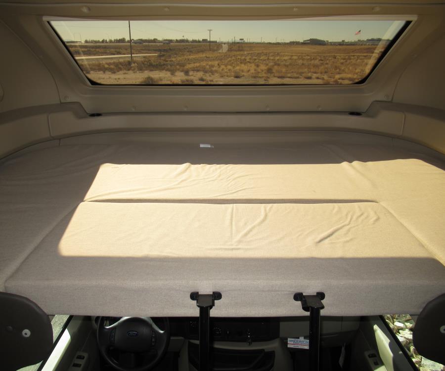 RV rental interior: View of the spacious cab-over bunk bed and the steering wheel below, with a desert landscape outside the window.. Entegra Coach Odyssey 24B 2020