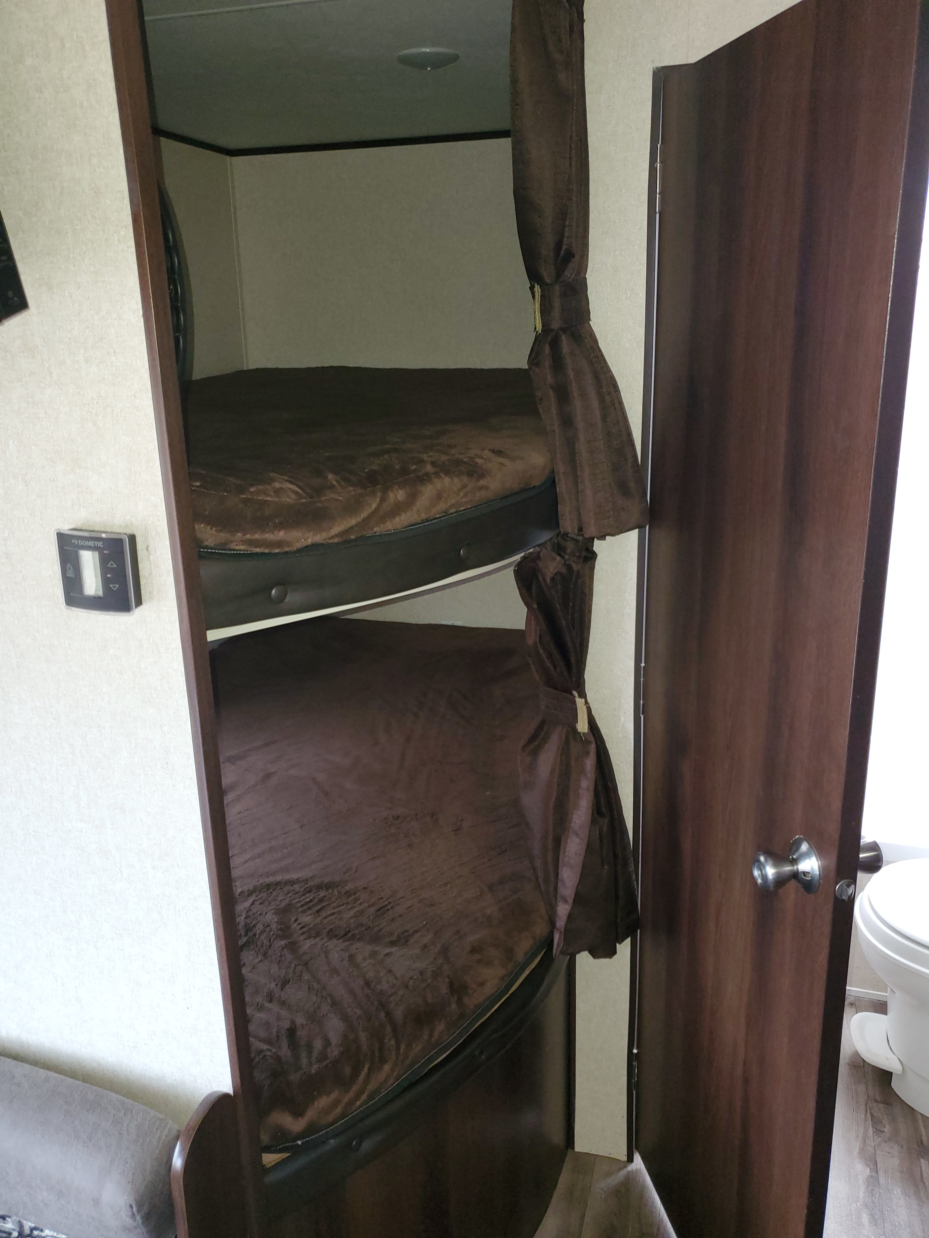 Inside this RV rental: bunk beds with privacy curtains. Adjacent door to a small bathroom with toilet.. Jayco for rent NEW 2019 Jayco 26 foot bunkhouse Rental sleeps 10 2019