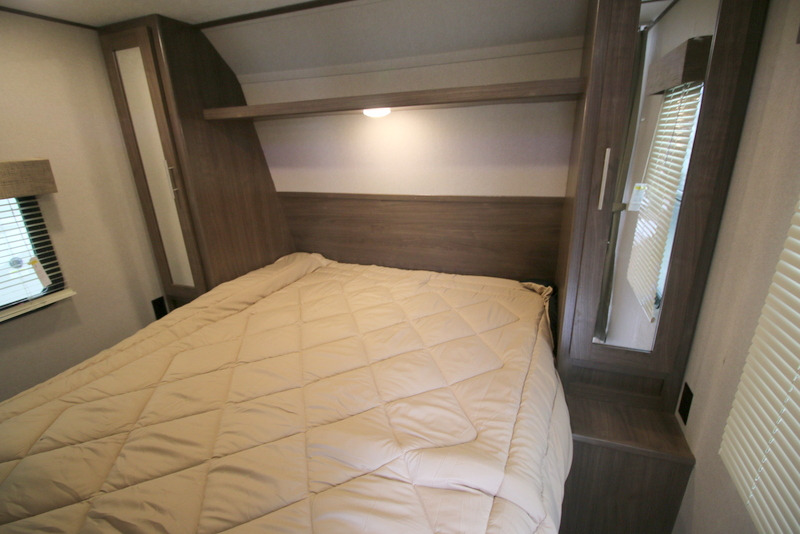 This RV rental bedroom features a cozy bed with a headboard, overhead shelf, and compact built-in storage.. Keystone Hideout 2020