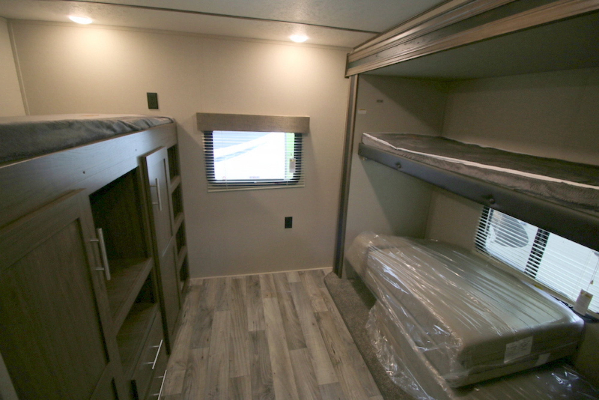 Inside an RV rental, a compact bunkhouse features multiple bunk beds, cabinetry, and a new, plastic-wrapped mattress.. Keystone Hideout 2020