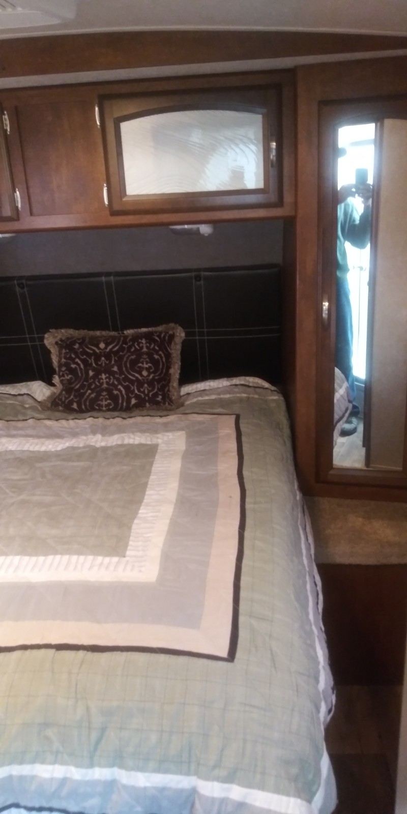 Cozy RV rental bedroom showcasing a comfortable bed, wood cabinets, and a mirrored closet.. Forest River Heritage Glen 2016