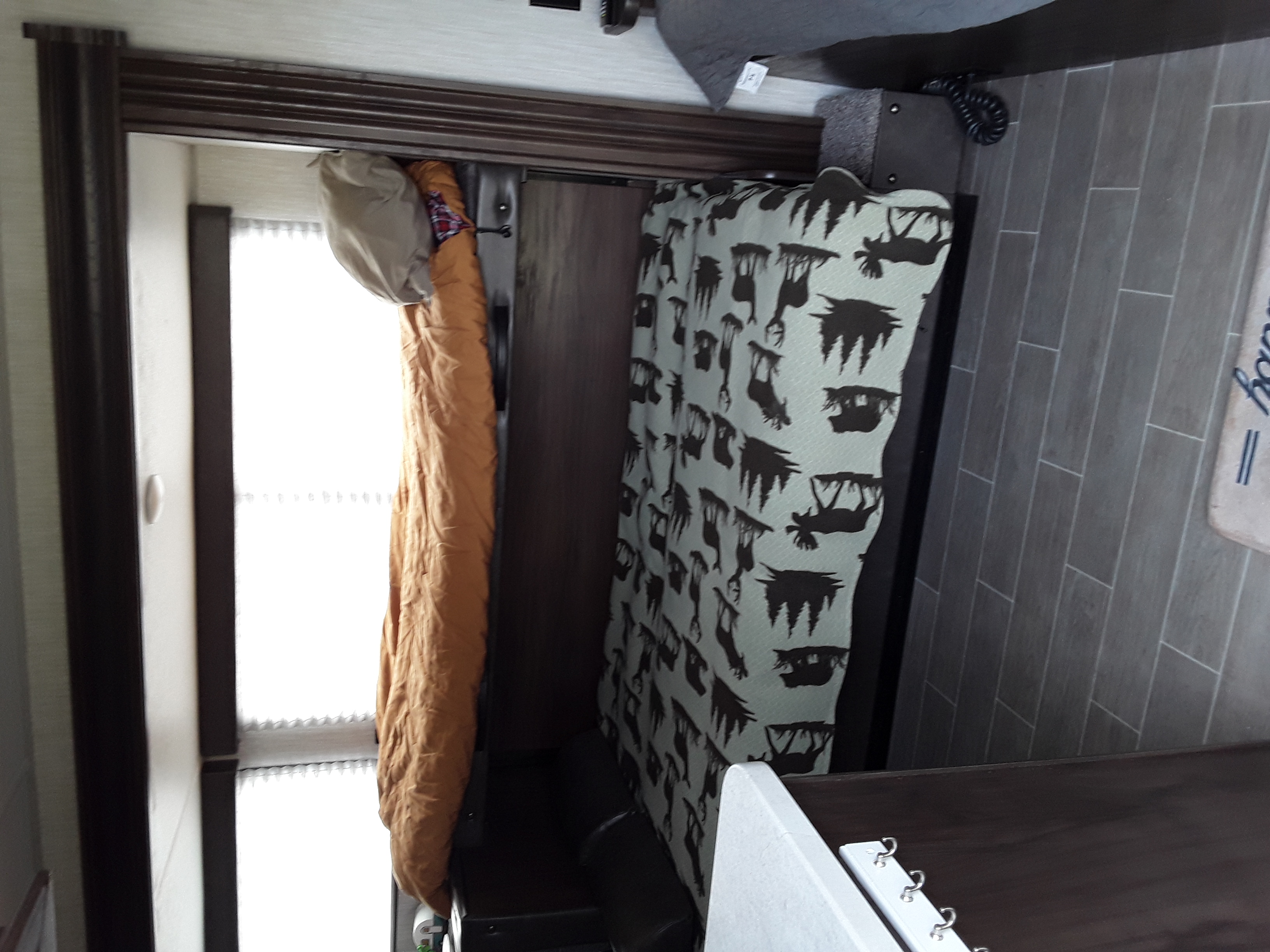 RV rental interior: Dinette seating with moose print and a bright sleeping area by the window, featuring plank flooring.. Forest River Wolf Pup 2020