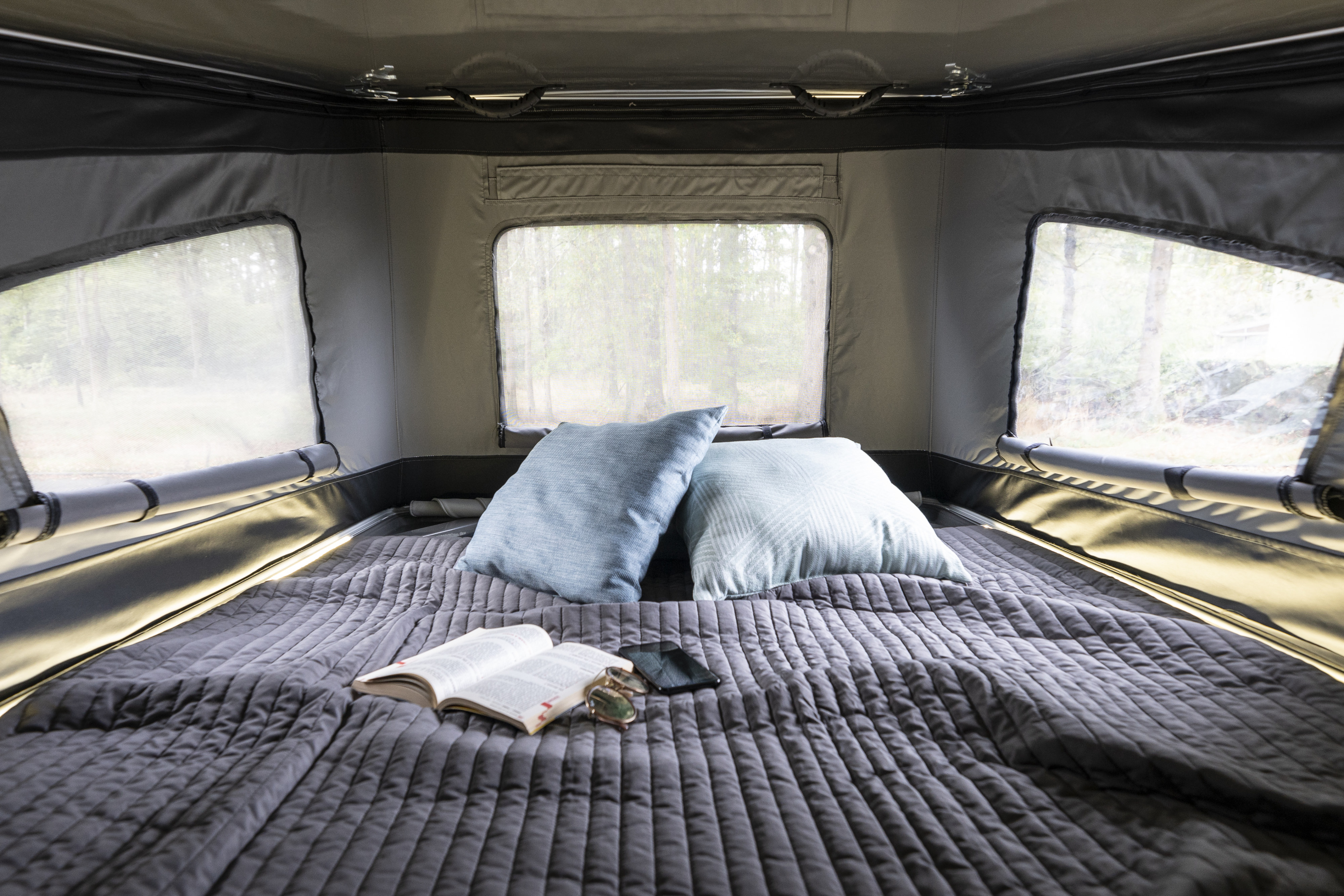 Relax in this RV rental's comfy interior featuring a bed, nature views from screened windows, and ambient lighting.. Hanroad Trek 2025