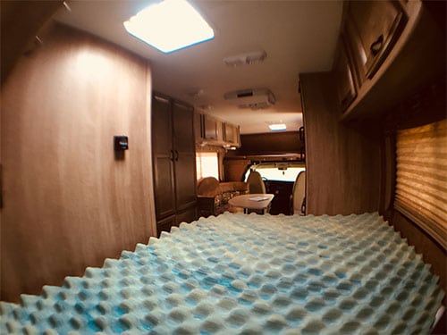 RV rental interior: Comfortable living space with a blue and white textured mattress topper, dining area, and front cabin.. Coachmen Freelander 2016