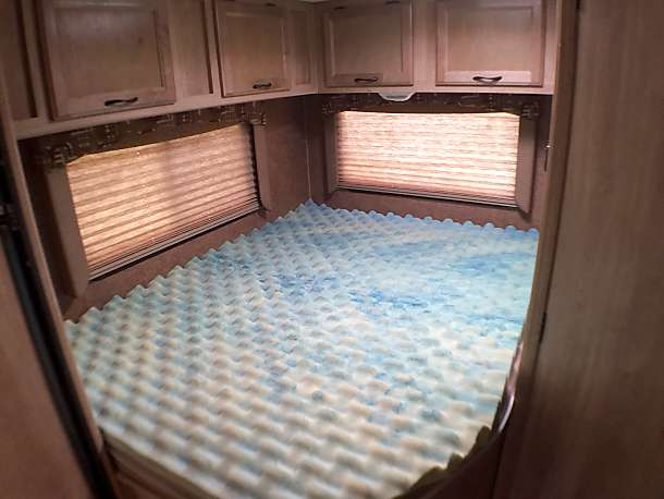 Comfortable RV rental bedroom with a foam mattress topper, overhead cabinets, and window blinds for a cozy sleep.. Coachmen Freelander 2016