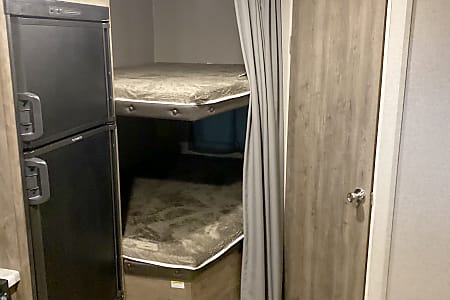 RV rental interior featuring practical bunk beds and a two-door refrigerator, perfect for family travel comfort.. Dutchmen Aspen Trail 2020