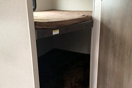 Inside an RV rental, showing two stacked bunk beds with brown mattresses, offering comfortable sleeping arrangements.. Dutchmen Aspen Trail 2020
