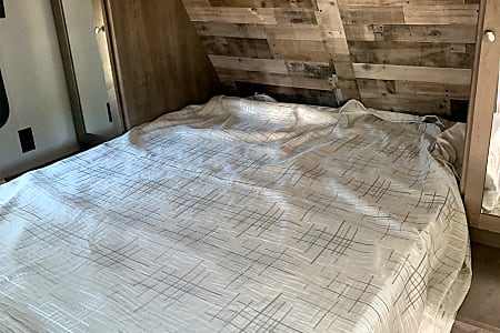 RV rental bedroom: Features a comfy bed with modern patterned bedding and a stylish wood-paneled headboard.. Dutchmen Aspen Trail 2020