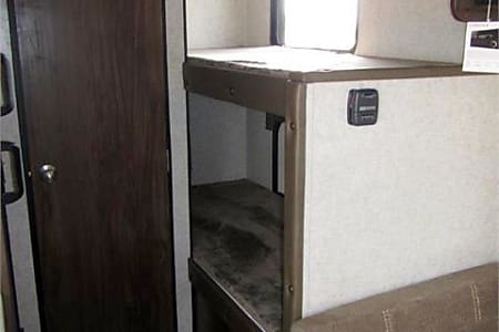 Interior of RV rental: A wooden door on the left, bunk beds on the right, maximizing compact living space.. Forest River Cherokee Wolf Pup 2019