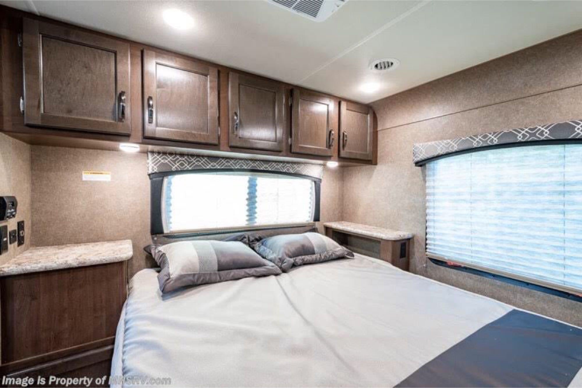 Experience comfort in this RV rental bedroom with a cozy bed, ample overhead cabinets, and bright windows.. Thor Motor Coach Chateau 2020