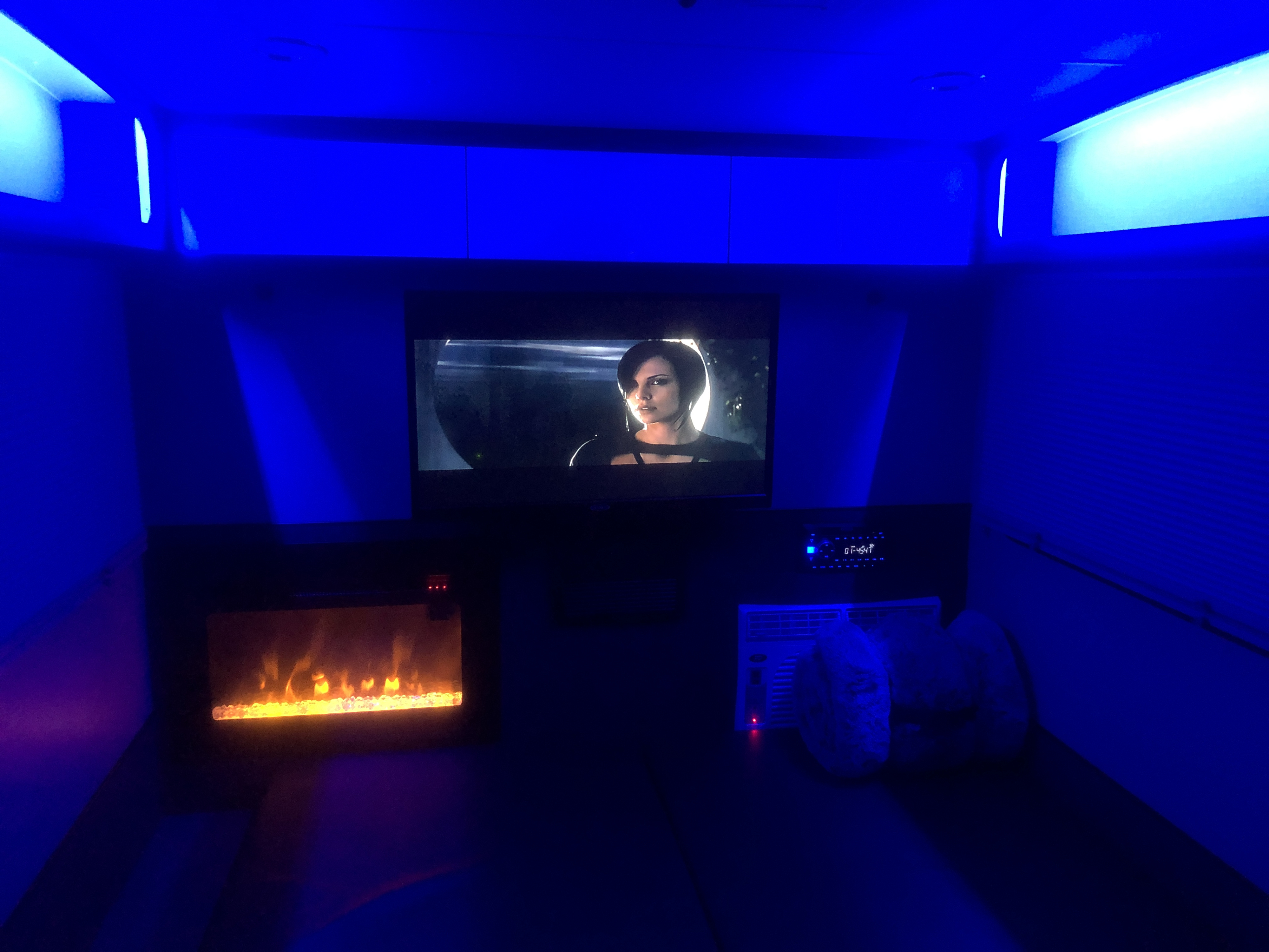 RV rental's cozy interior: blue lighting, TV with a movie, and an electric fireplace creating a relaxing atmosphere.. InTech RV InTech RV Trailer 2021