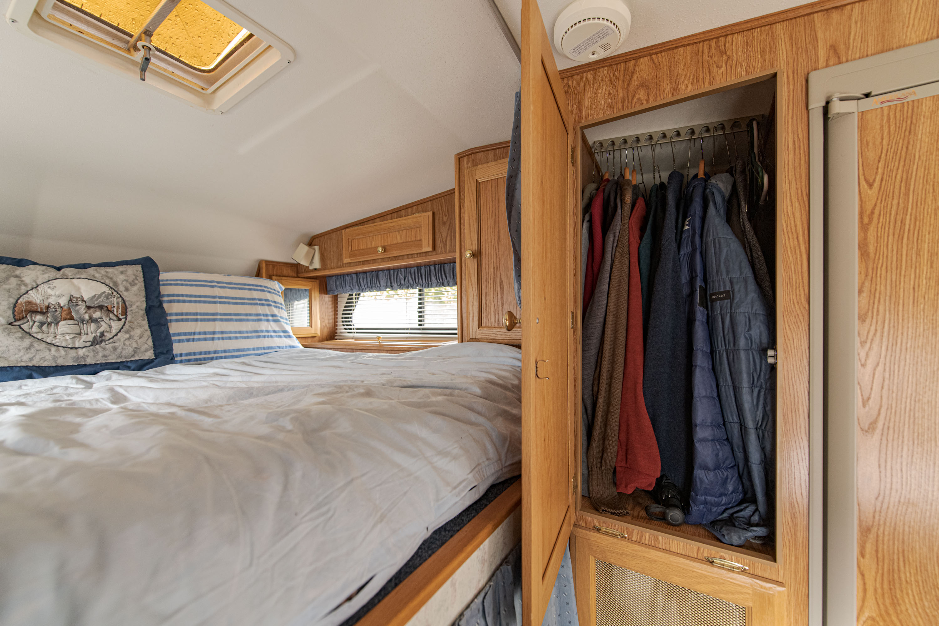 Cozy RV rental bedroom with wooden cabinetry, a comfortable bed, and ample closet space for your travel essentials.. Ford Other 1995