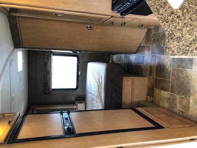Inside an RV rental: view of the well-appointed kitchenette, tiled floor, and comfortable bedroom area.. Thor Motor Coach Freedom Elite 2016
