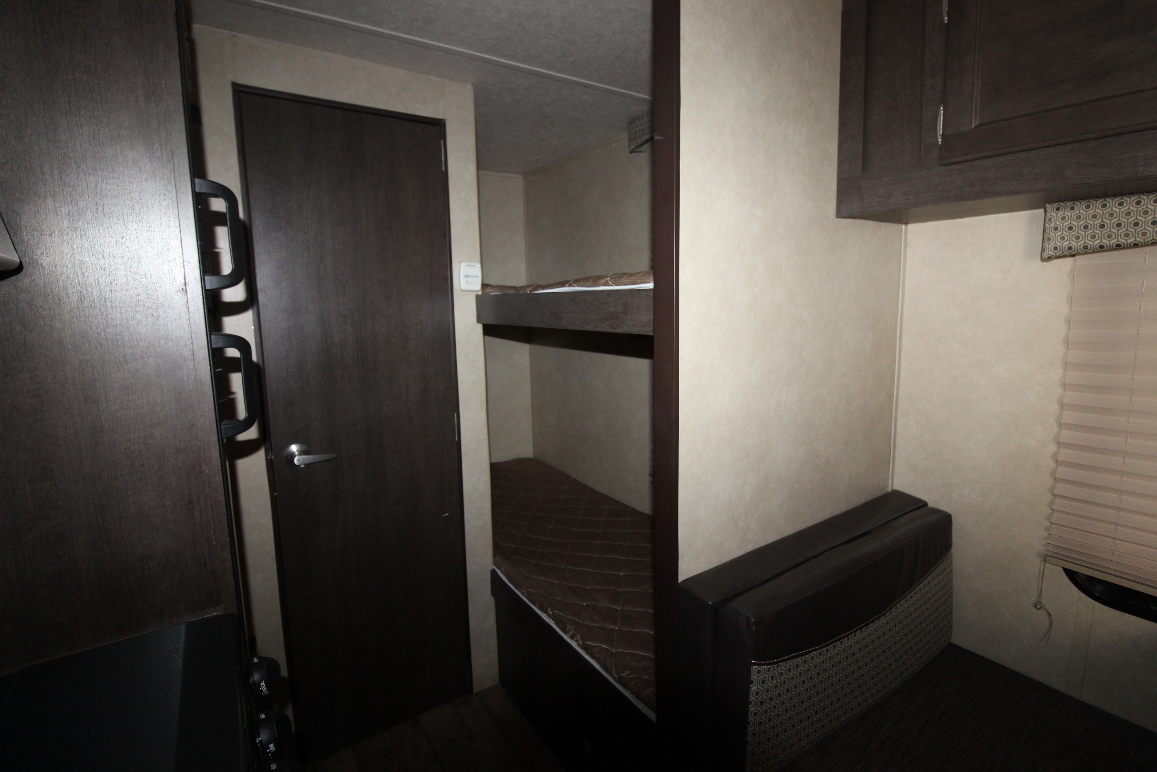 rv rental: Compact RV interior with dark wood bunk beds, a dark door, small seating area, and overhead cabinets.. Forest River Sonoma 2017