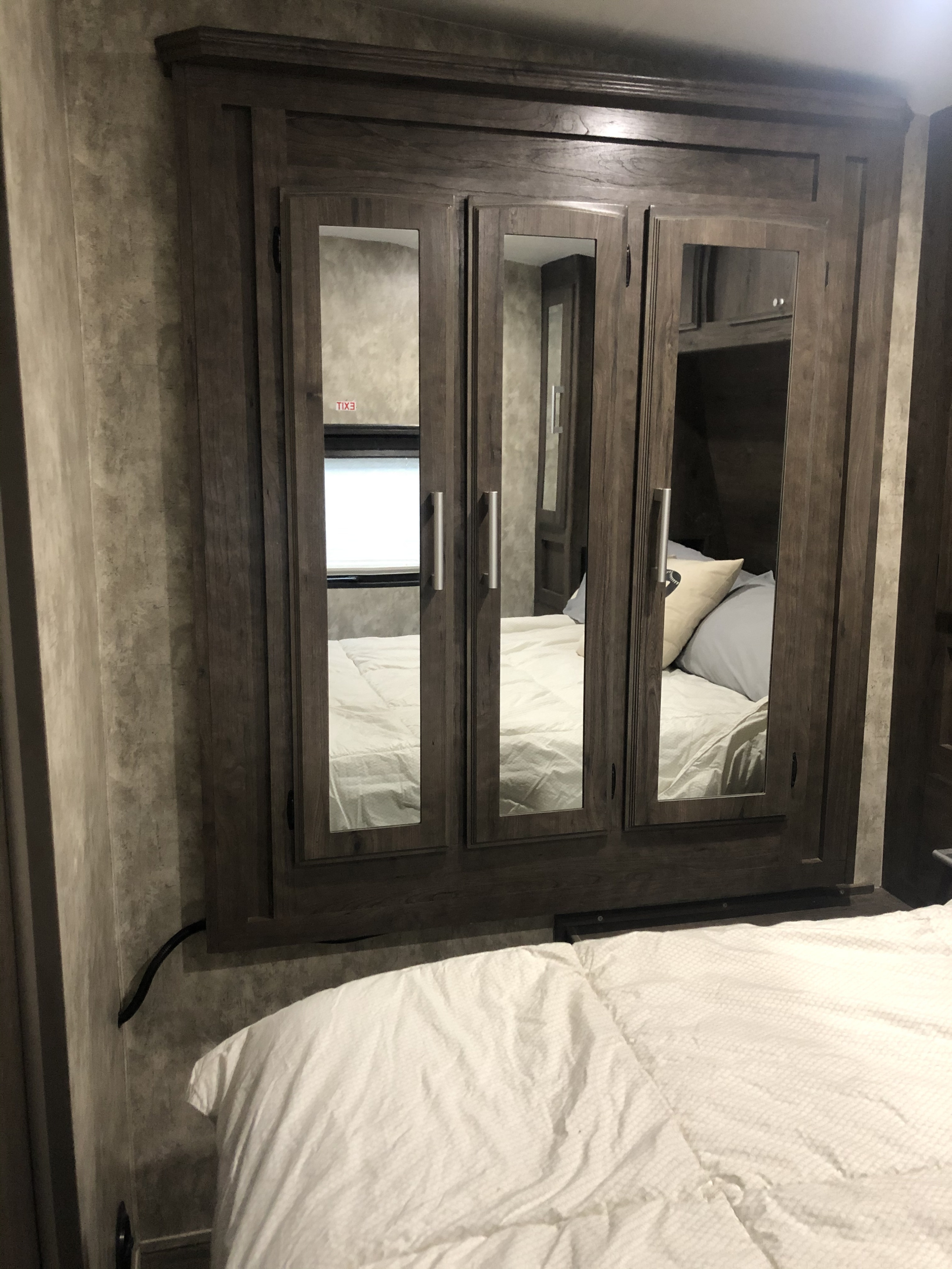 RV rental bedroom featuring a built-in mirrored wardrobe, reflecting comfortable white bedding in a compact space.. Eclipse Recreational Vehicles Attitude2814 2019