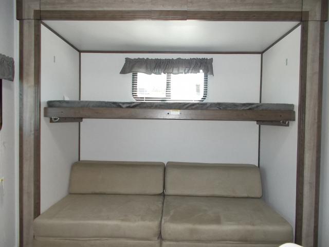 RV rental: a bunk bed above a beige convertible sofa provides versatile sleeping accommodations in this functional interior.. Keystone Passport 2020