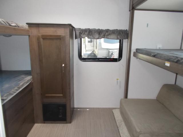 Cozy RV rental interior showing bunk beds, a storage cabinet, window, and sofa, perfect for adventure.. Keystone Passport 2020
