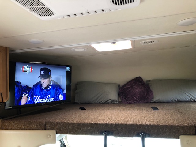 RV rental bunk with TV showing Yankees baseball, perfect for a cozy trip.. Thor Motor Coach Freedom Elite 2016