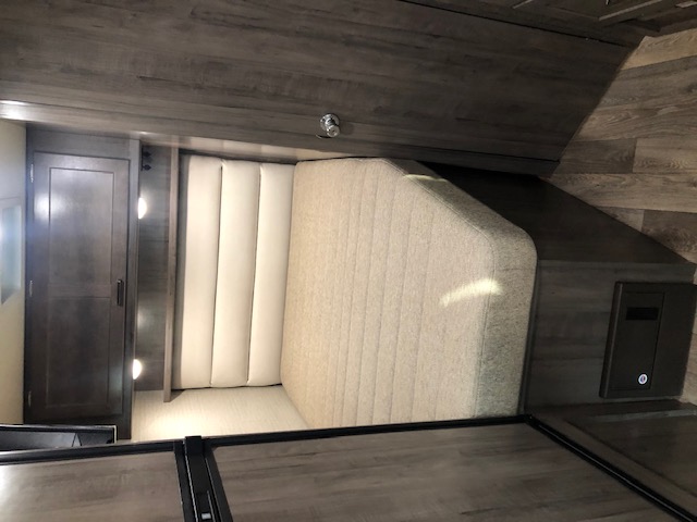 Modern RV rental bedroom with a comfortable bed, light padded headboard, and dark wood storage/cabinets.. Winnebago Minnie Winnie 2020