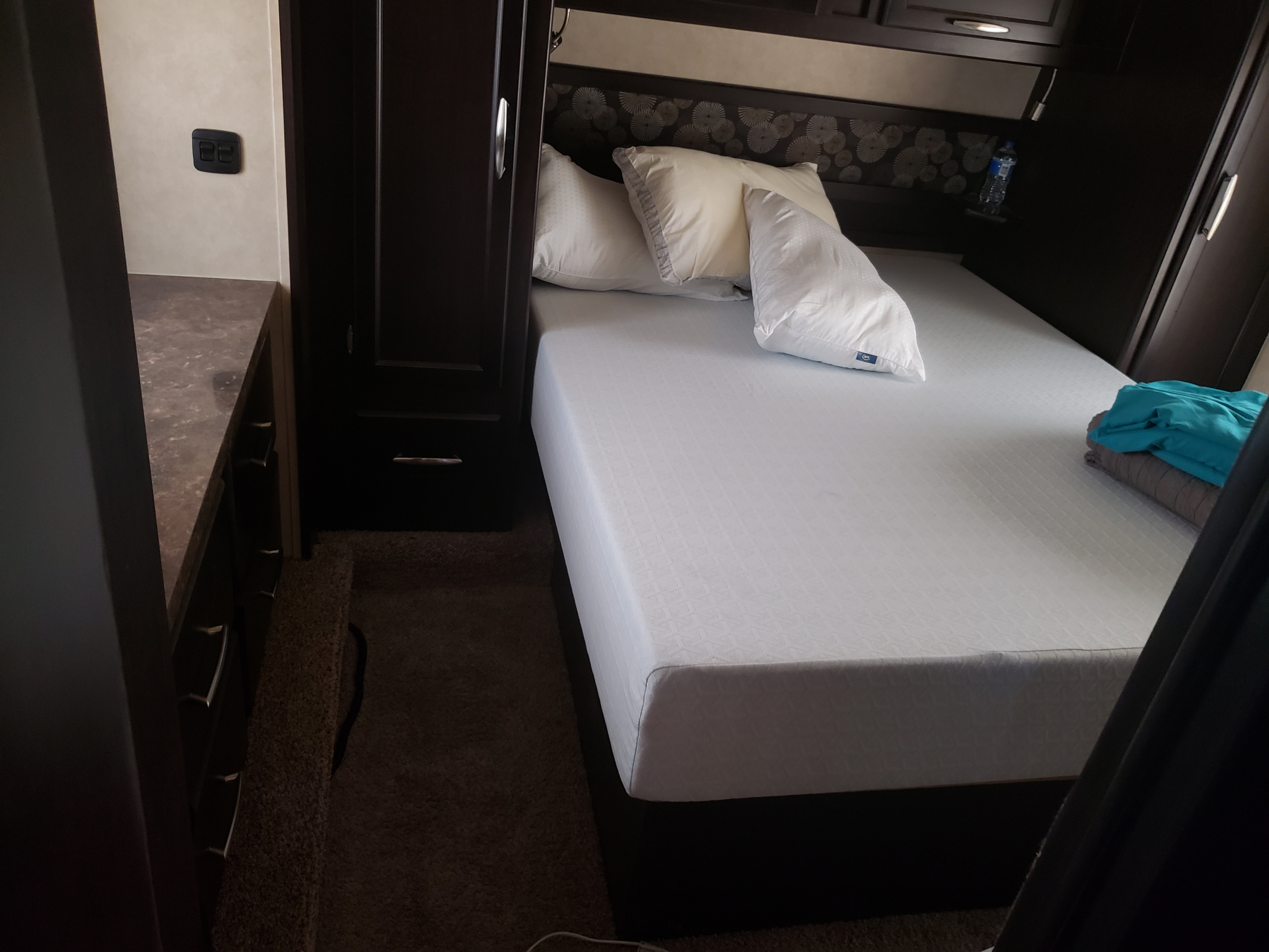 Inside an RV rental: a compact bedroom with a crisp white bed, built-in storage, and essential controls.. Genesis Supreme Rv Genesis Supreme 2016