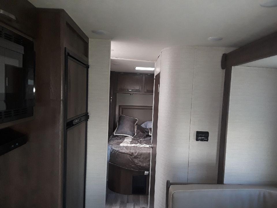 Cozy RV rental interior with kitchen amenities, a compact bedroom, and living area for comfortable travel.. Jayco Redhawk 2019