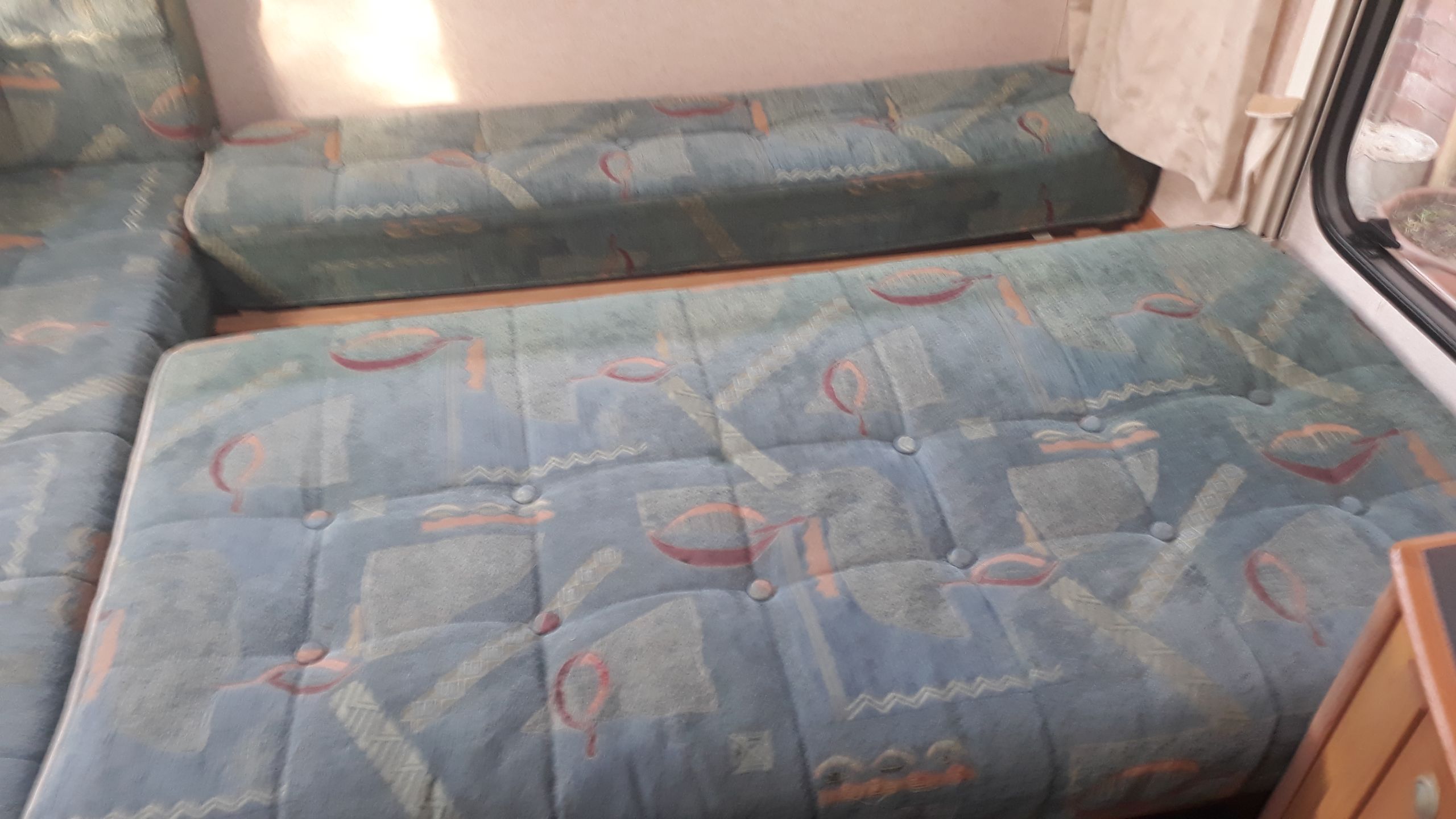 RV rental interior with light blue patterned, tufted cushioned seating and a window.. Fiat Ducato Swift Suntor 2000