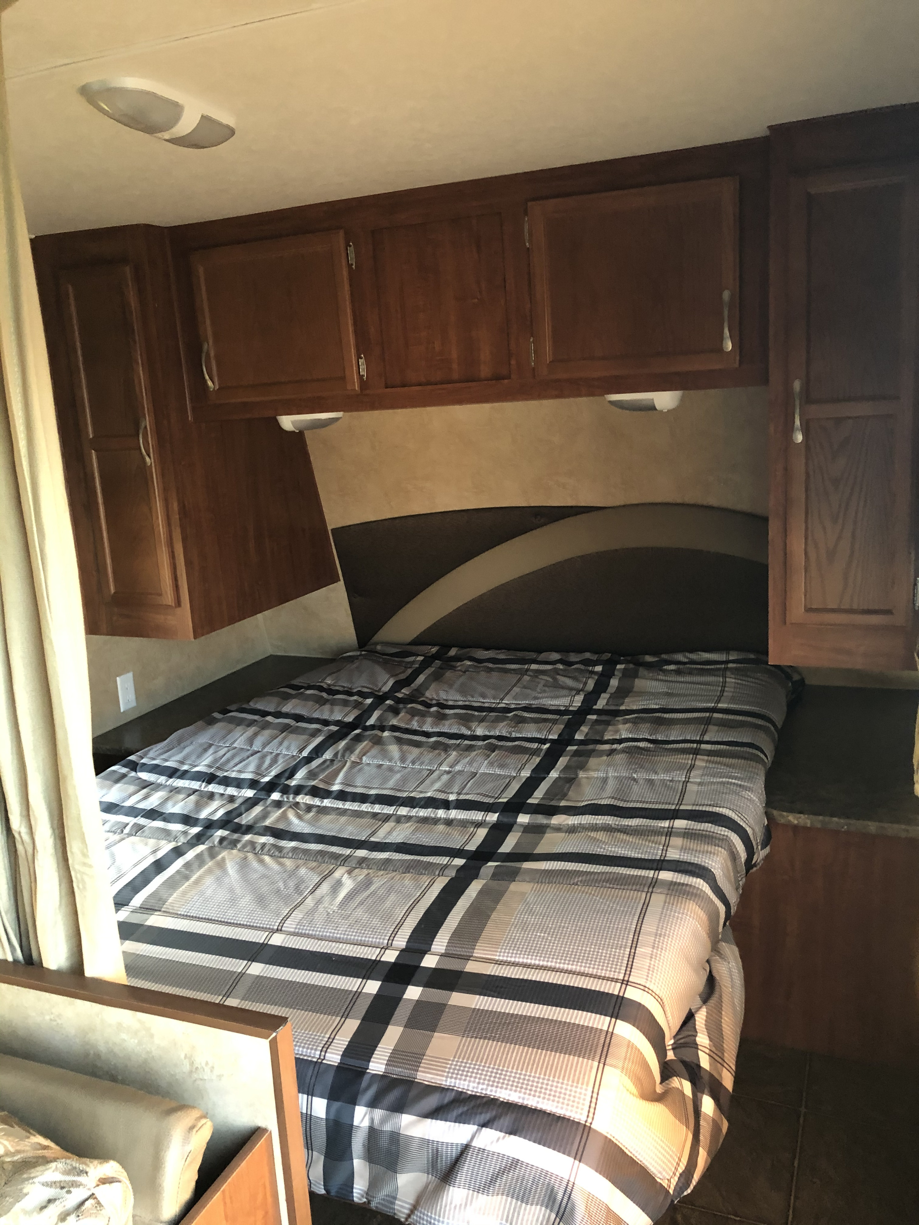 Comfortable RV rental bedroom with plaid bedding, overhead cabinets, and built-in storage, perfect for your next road trip.. Jayco Jay Flight 2011