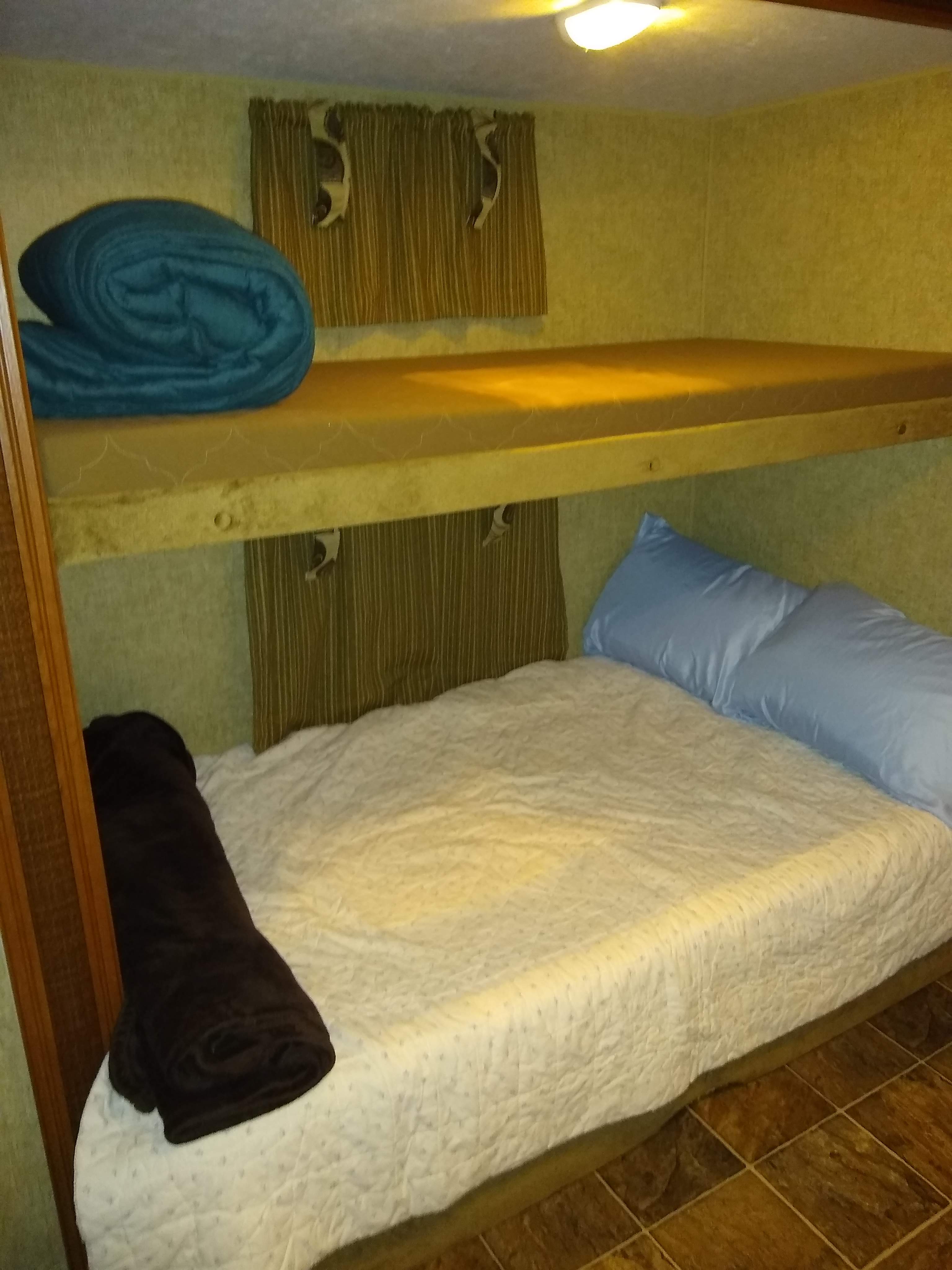 Inside an RV rental: upper and lower bunk beds with cozy bedding and pillows, perfect for mobile sleeping.. Other Other 2014