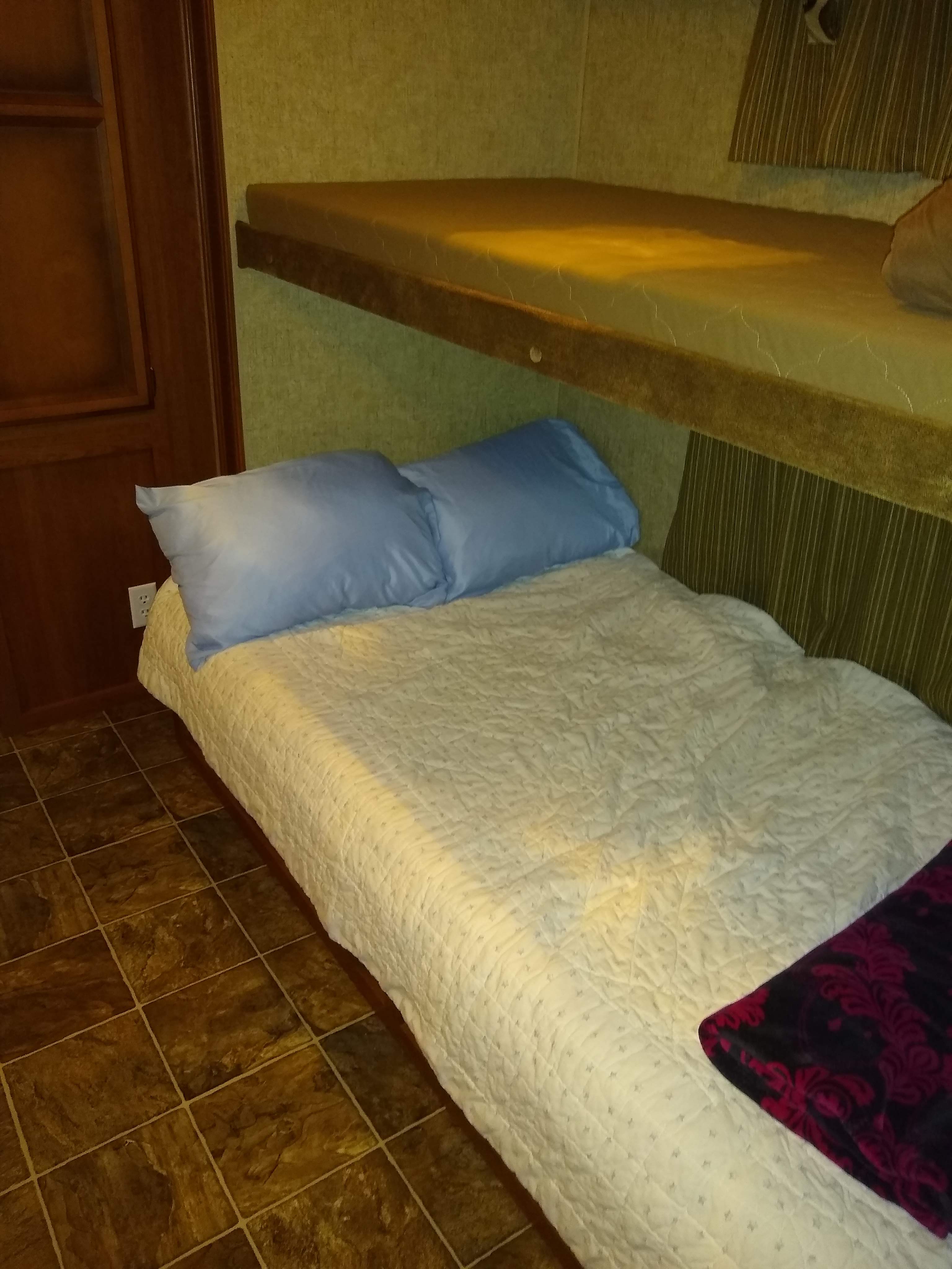 RV rental bunk beds provide cozy sleeping arrangements. Features a lower bunk with pillows and quilt, and an upper bunk.. Other Other 2014