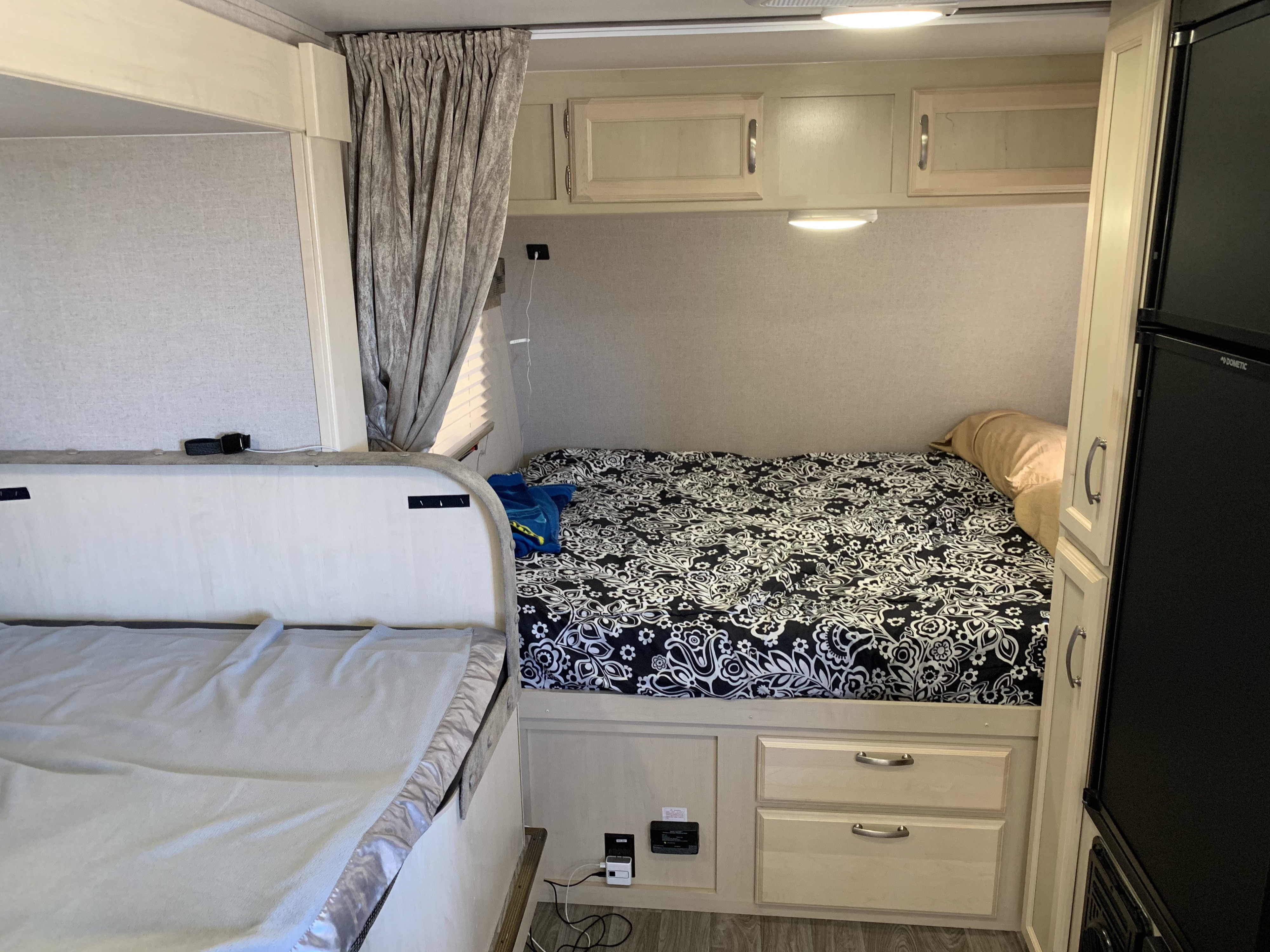 RV rental camper bedroom featuring bunk beds, overhead storage, a compact fridge, and charging outlets.. Other Other 2019