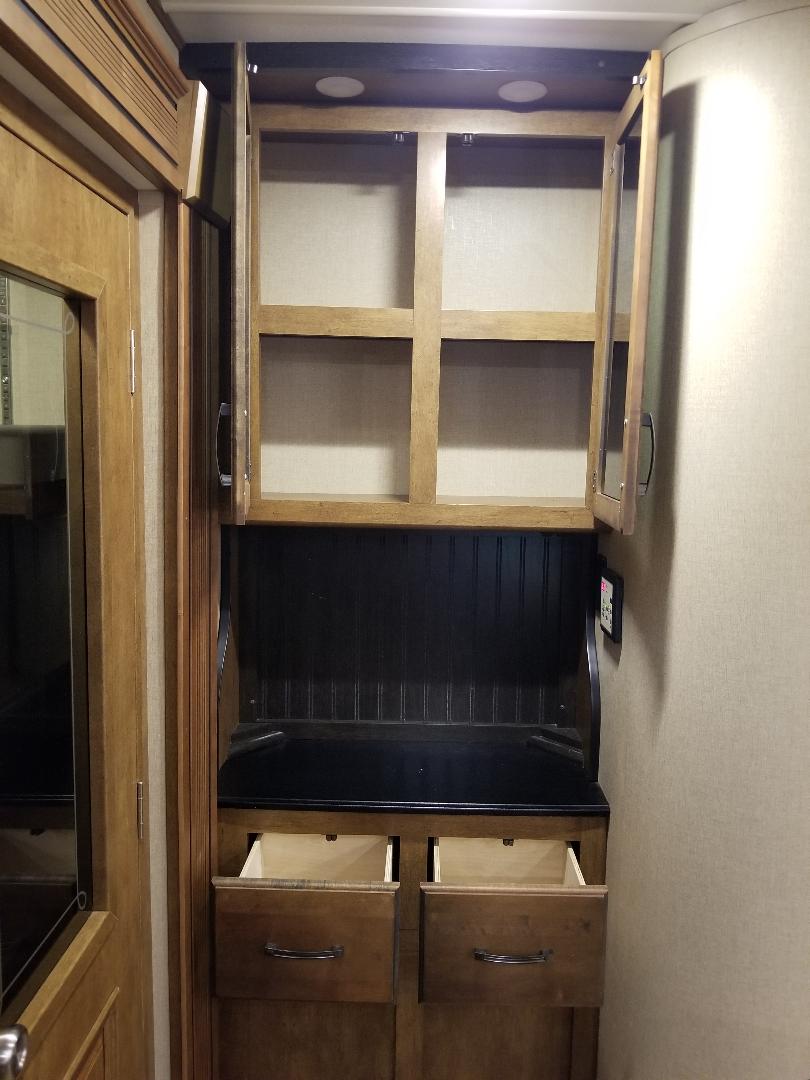 RV rental storage: Wooden unit with open cabinets, a compact desk, and pull-out drawers for organized RV living.. Grand Design Reflection 2015