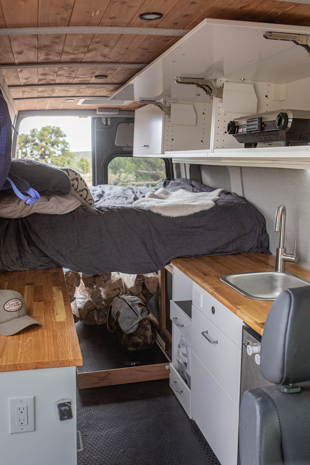 RV rental interior: cozy bed, full kitchen w/ sink, wooden counters, overhead projector, and under-bed storage.. Mercedes-Benz Sprinter 2018
