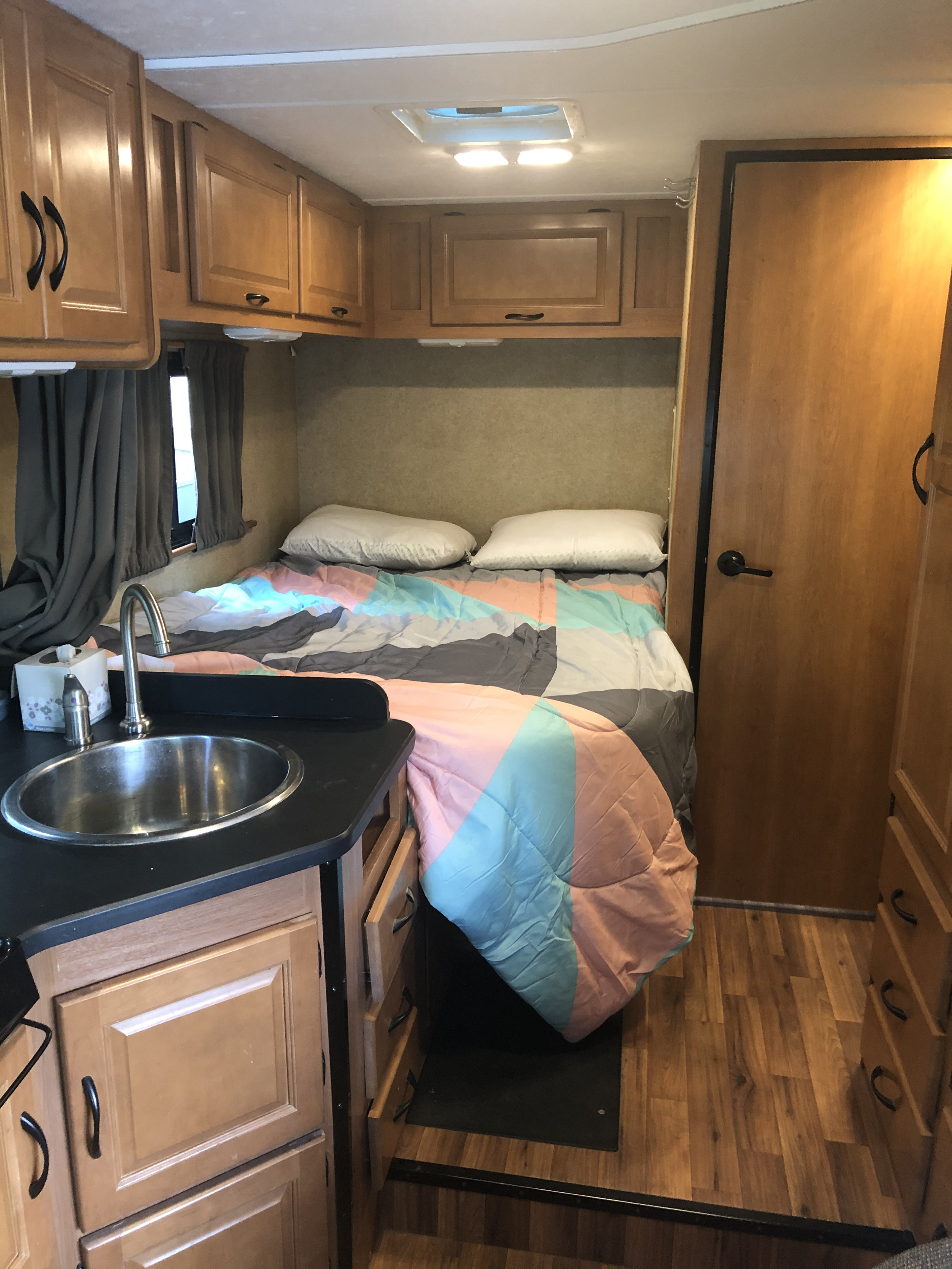 Cozy rv rental interior featuring a comfortable bed, small kitchen sink, and ample storage cabinets.. Thor Motor Coach Four Winds Majestic 2015