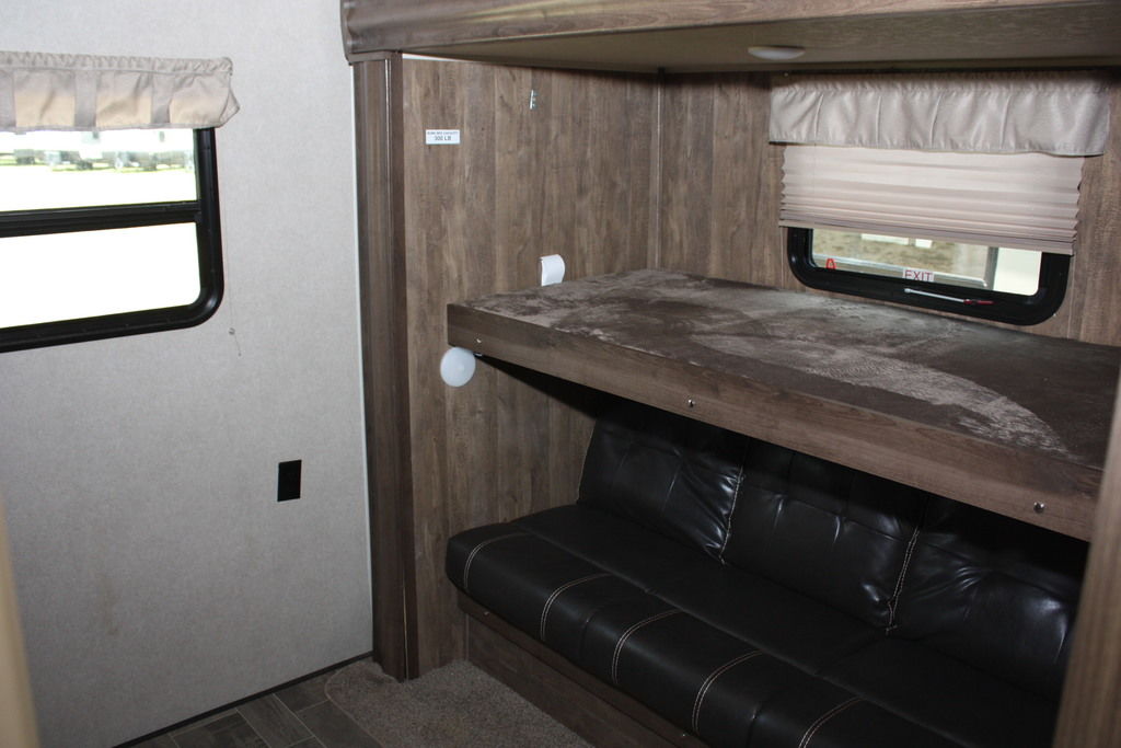 An RV rental interior showing bunk beds (upper bunk and lower convertible couch) and windows. Ideal for travel.. Palomino Puma 2018