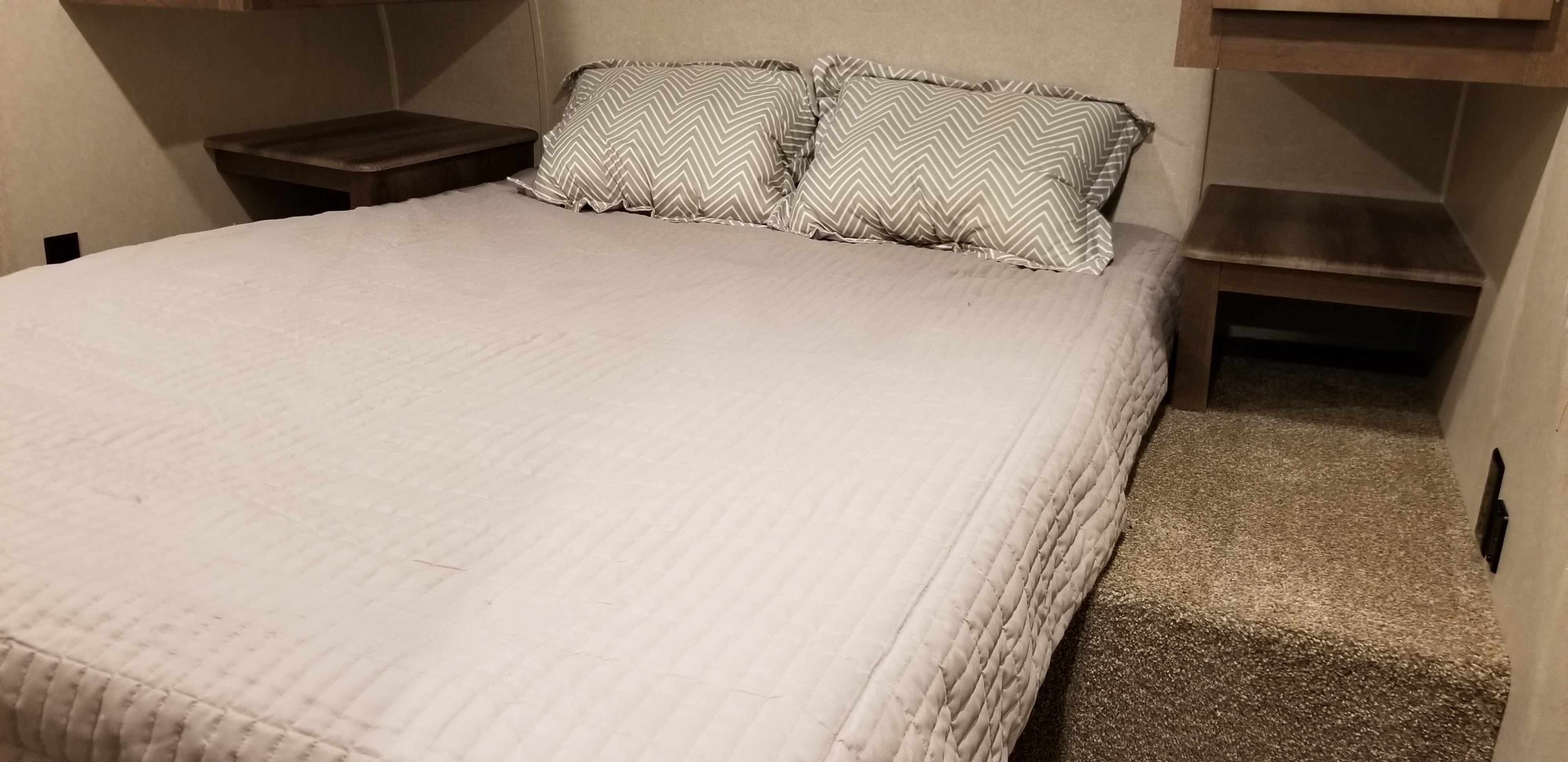 Comfortable RV rental bedroom with queen bed, chevron pillows, and side shelves. Perfect for a good night's sleep on the road.. Palomino Puma 2018
