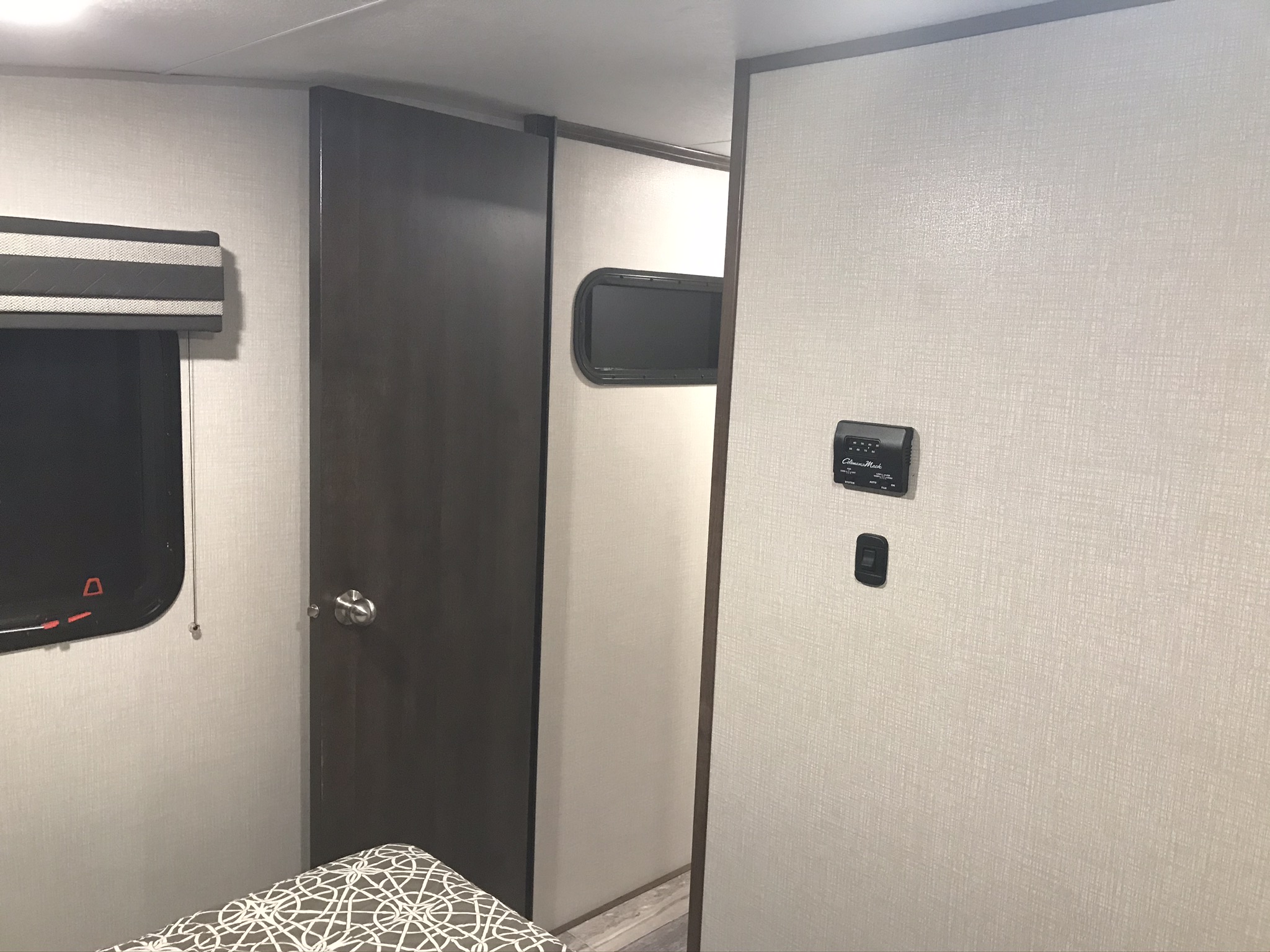 RV rental interior: cozy bedroom with a door, window, and climate controls, offering comfort on your journey.. K-Z Manufacturing Durango 2020