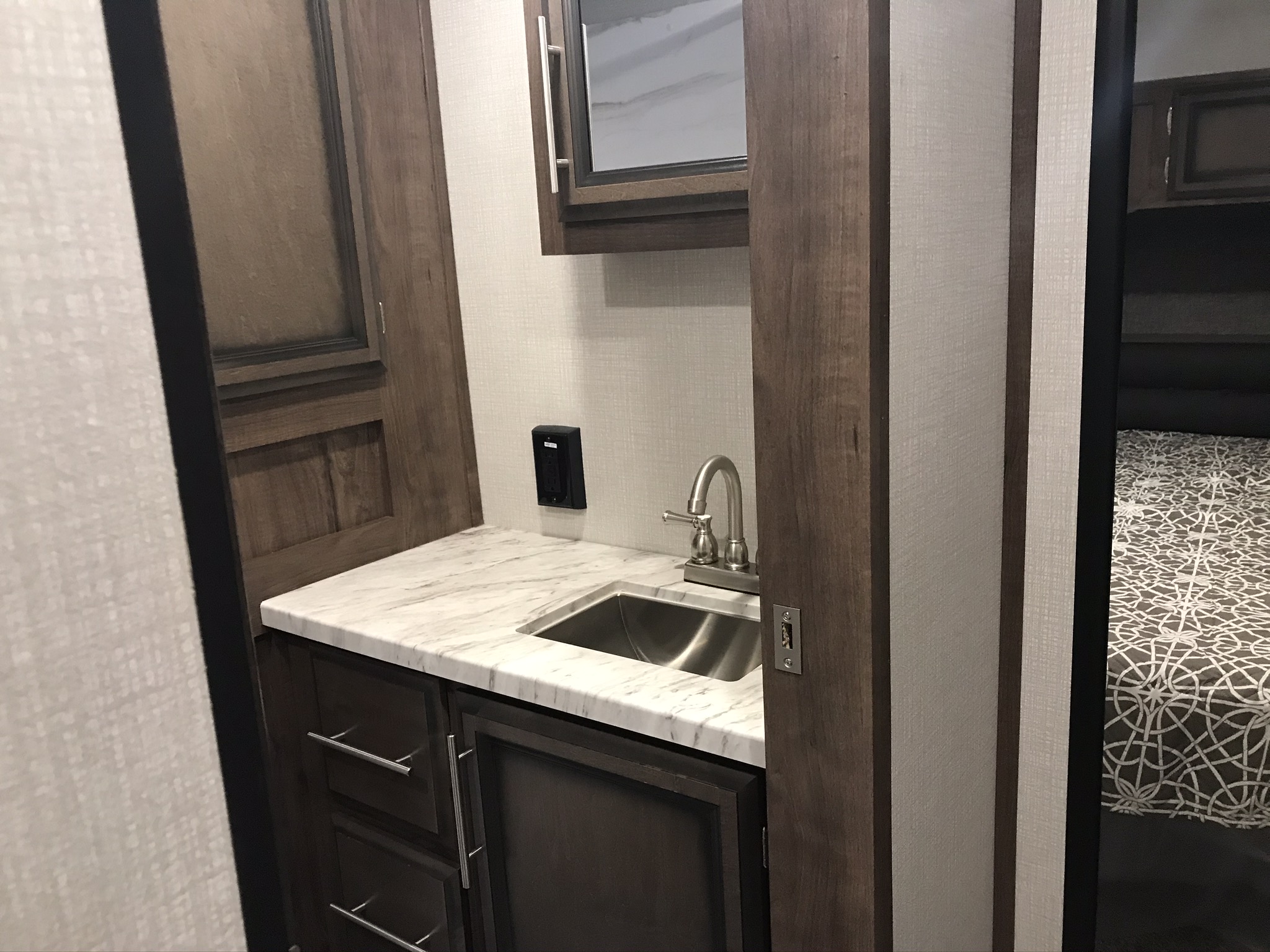 Compact RV rental interior featuring a modern kitchenette with a stainless steel sink, cabinets, and a glimpse of the bedroom. Functional space.. K-Z Manufacturing Durango 2020
