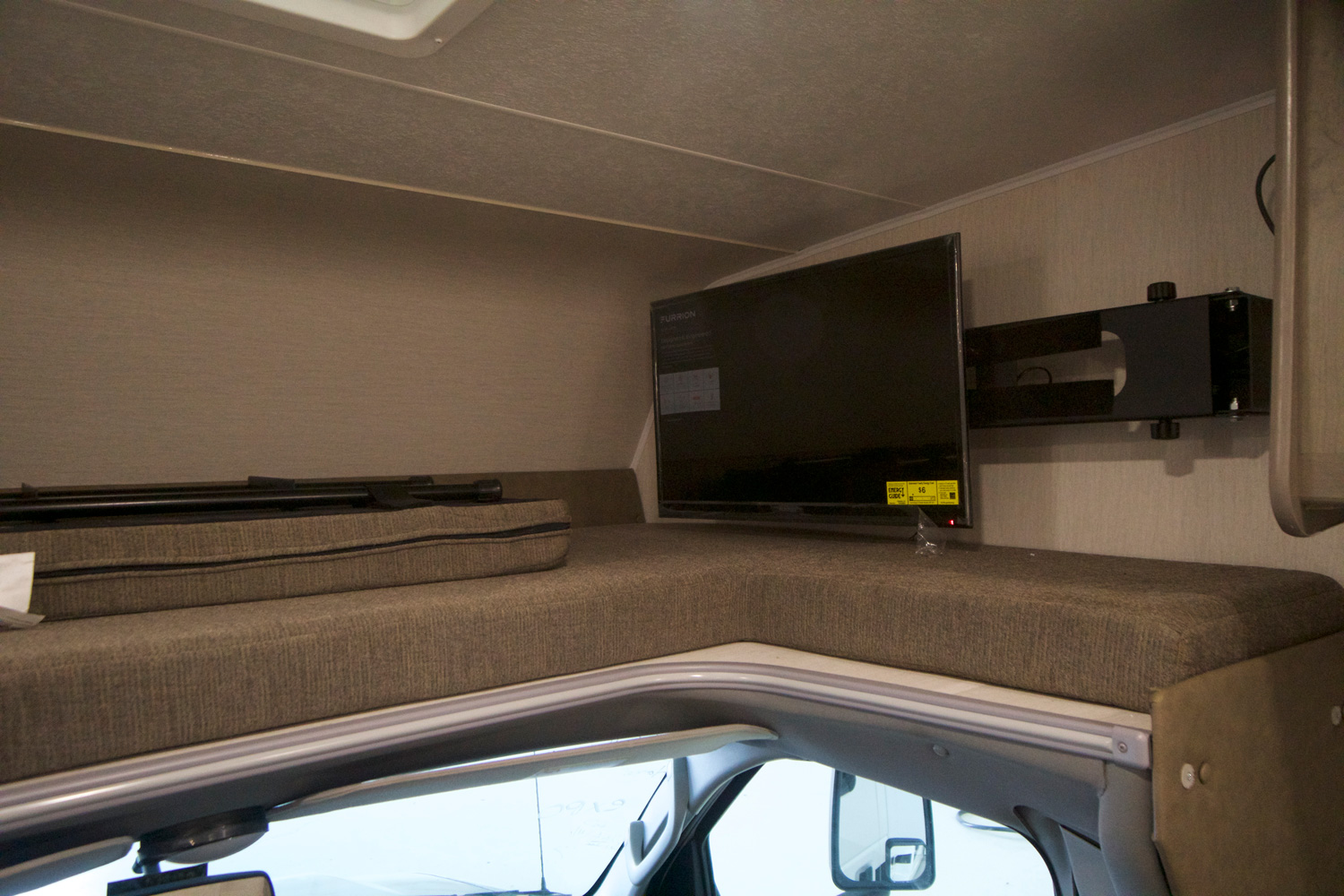 Inside this RV rental, the cab-over bunk features a wall-mounted TV and a folded bed support, ready for use.. Coachmen Freelander 2020