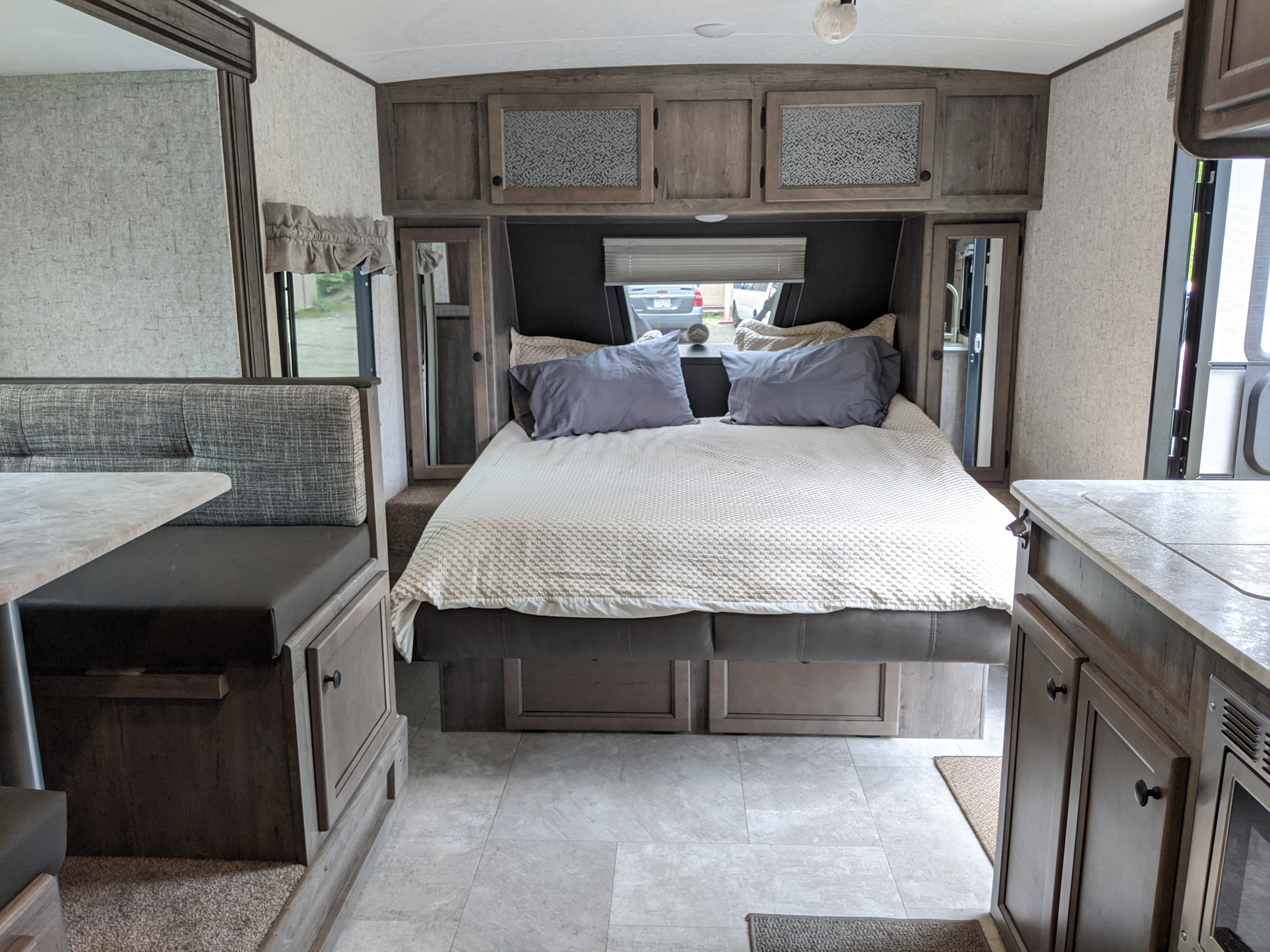 Spacious RV rental interior featuring a cozy bedroom, dinette seating, and kitchenette, ideal for comfortable travel.. Coachmen Apex 2021