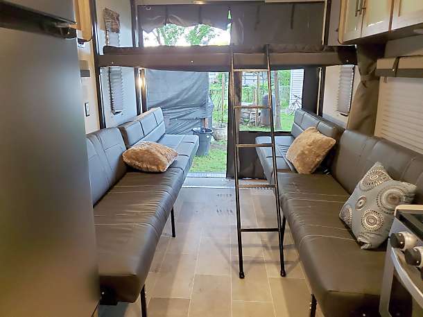 Spacious RV interior with convertible seating, bunk bed, and large rear ramp. Perfect for an RV rental adventure.. Palomino Puma 2020