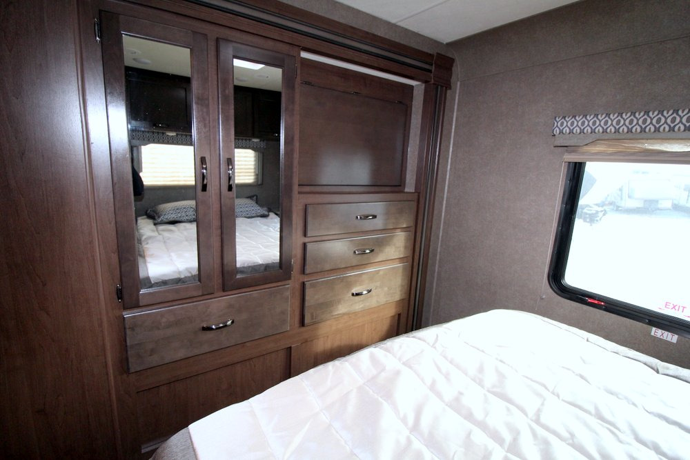 RV rental bedroom interior: features a cozy bed, mirrored wardrobe with drawers, and window. Efficient compact living space.. Thor Motor Coach Freedom Elite 30FE 2020