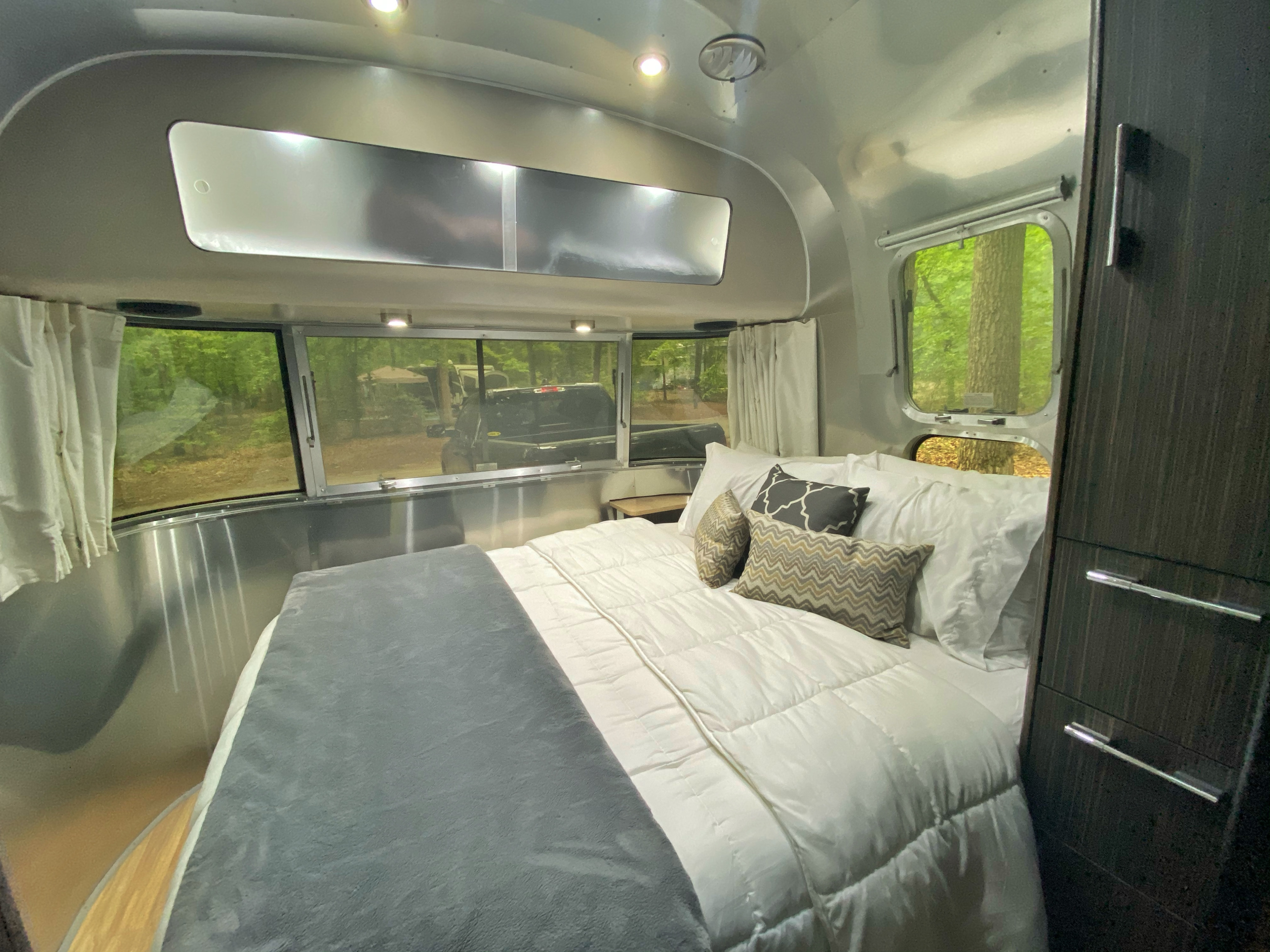 Bright and inviting Airstream rv rental bedroom. Enjoy the comfy bed and views of nature from wide windows.. Airstream International 2019