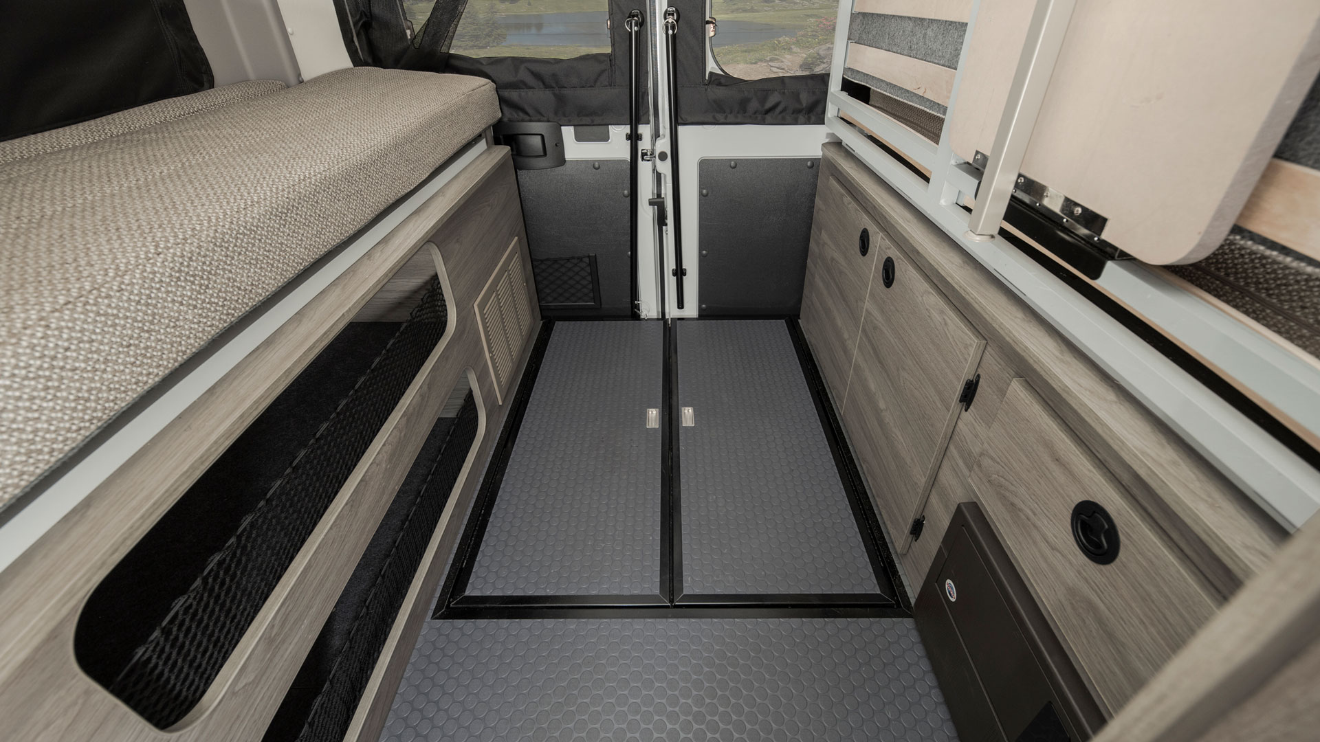 Inside an RV rental: a modern camper van interior with sleeping/seating, ample storage, and rear view.. Winnebago Solis 2021