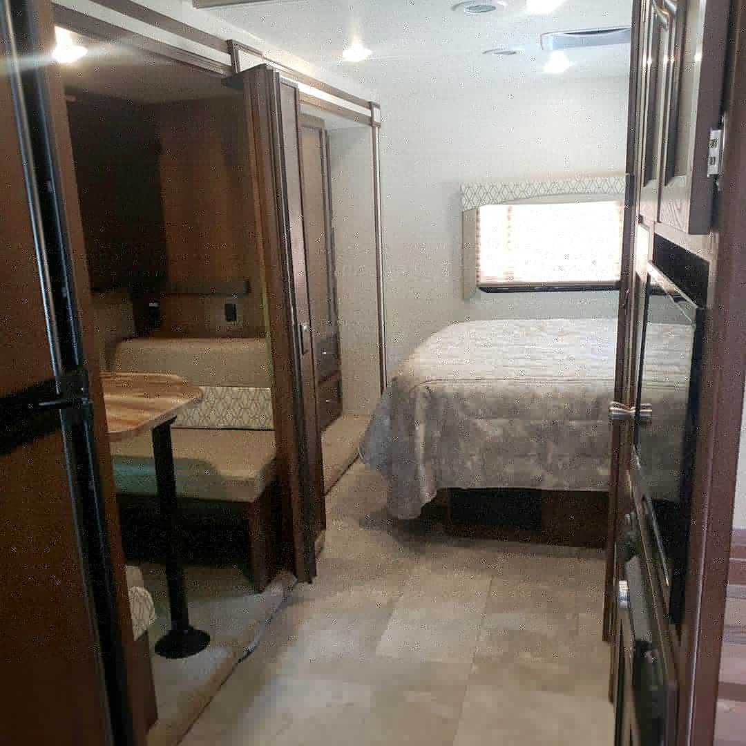 Spacious RV rental interior with a cozy bedroom and dinette area, perfect for your next adventure.. Coachmen Freelander 2020