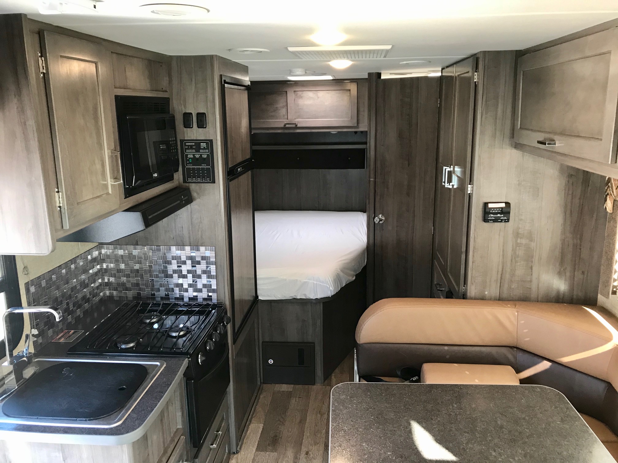 Explore this modern RV rental interior featuring a well-equipped kitchen, comfortable bedroom, and cozy dinette area.. Winnebago Minnie Winnie 2019