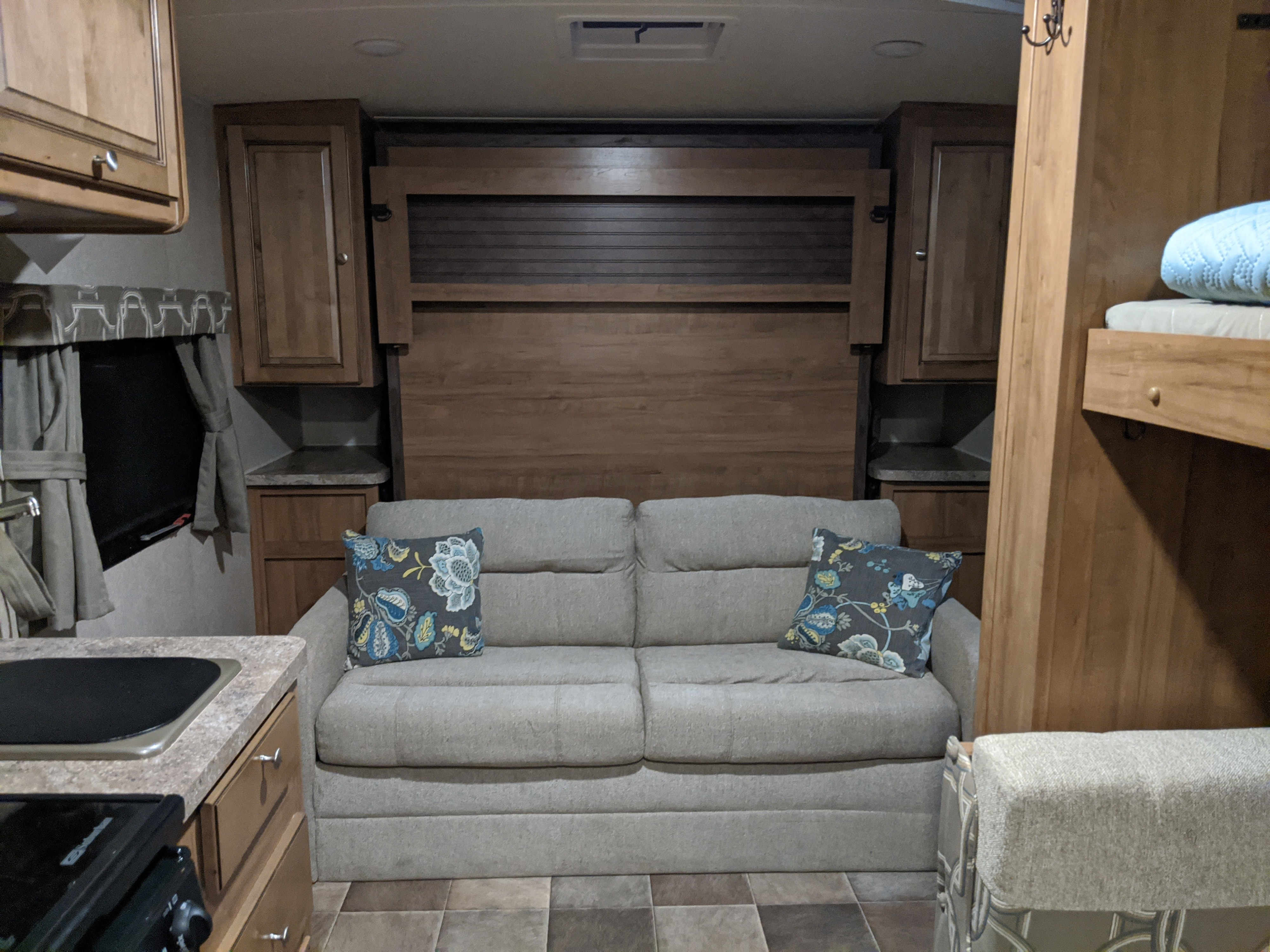 This RV rental interior features a comfortable sofa, wood cabinetry, a kitchen area, and bunk beds.. Flagstaff Micro Lite 2016