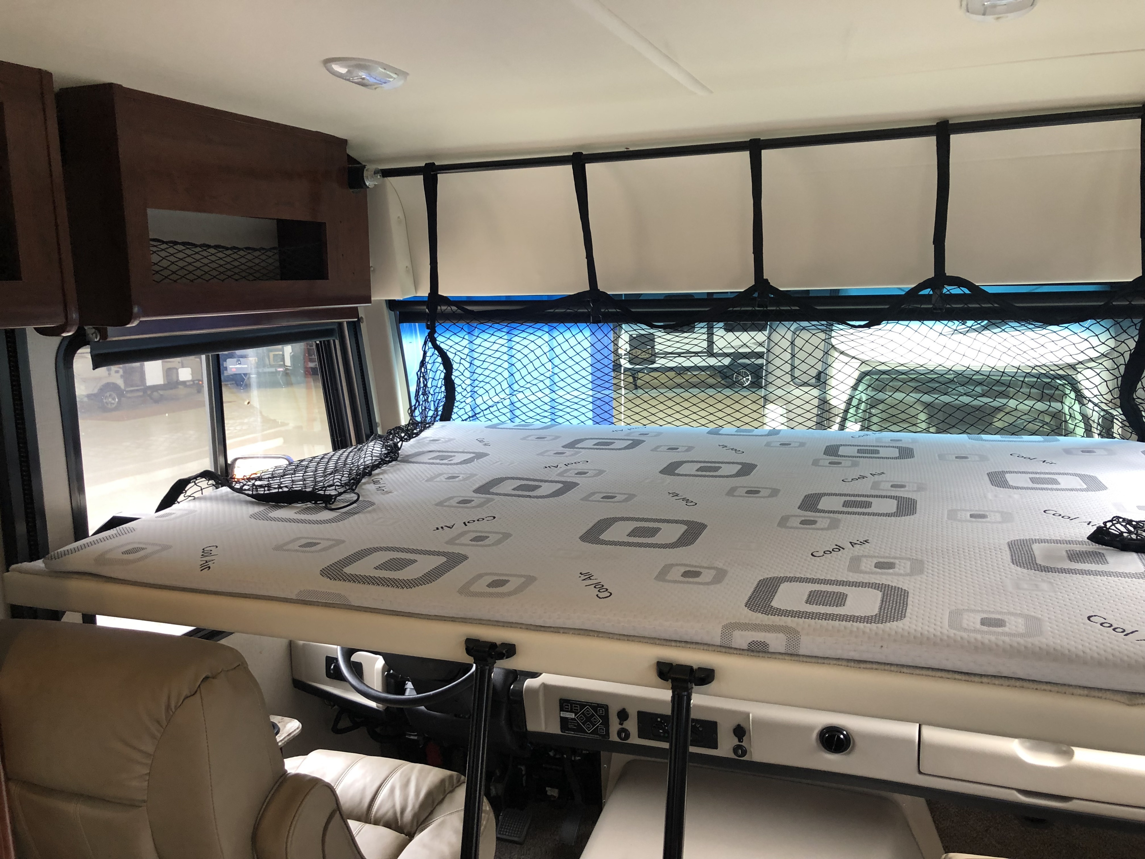 Inside an RV rental: view of the comfy overhead bunk bed with safety net, driver's area below. Great for family road trips.. HolidayRambler Admiral 2019