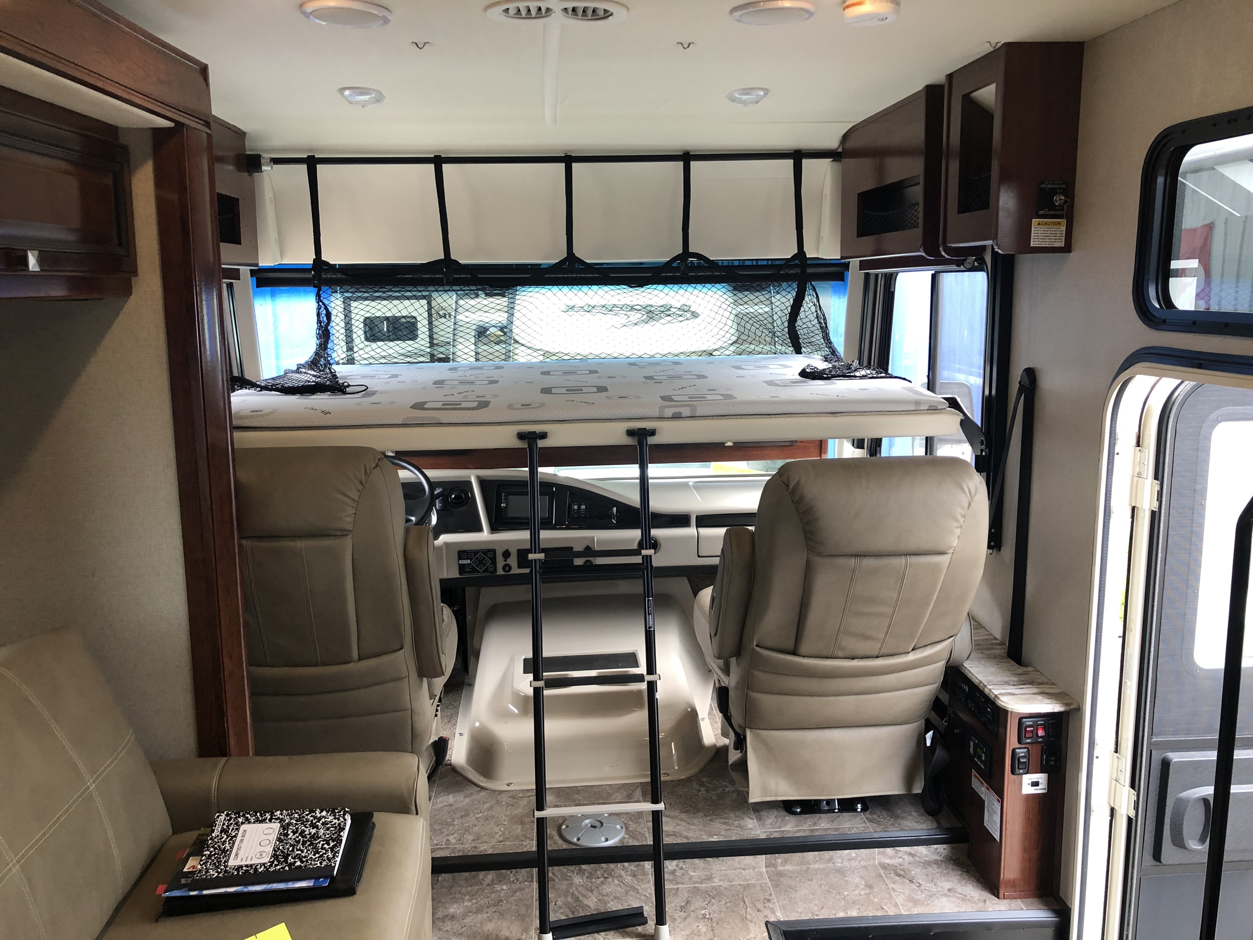 This RV rental interior features an elevated bunk bed with ladder, cockpit area, and lounge seating. Ready for adventure!. HolidayRambler Admiral 2019
